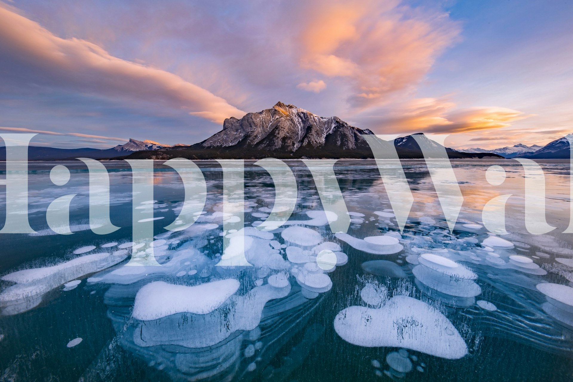Mountain silhouettes and colorful clouds reflect on icy blue lake wallpaper