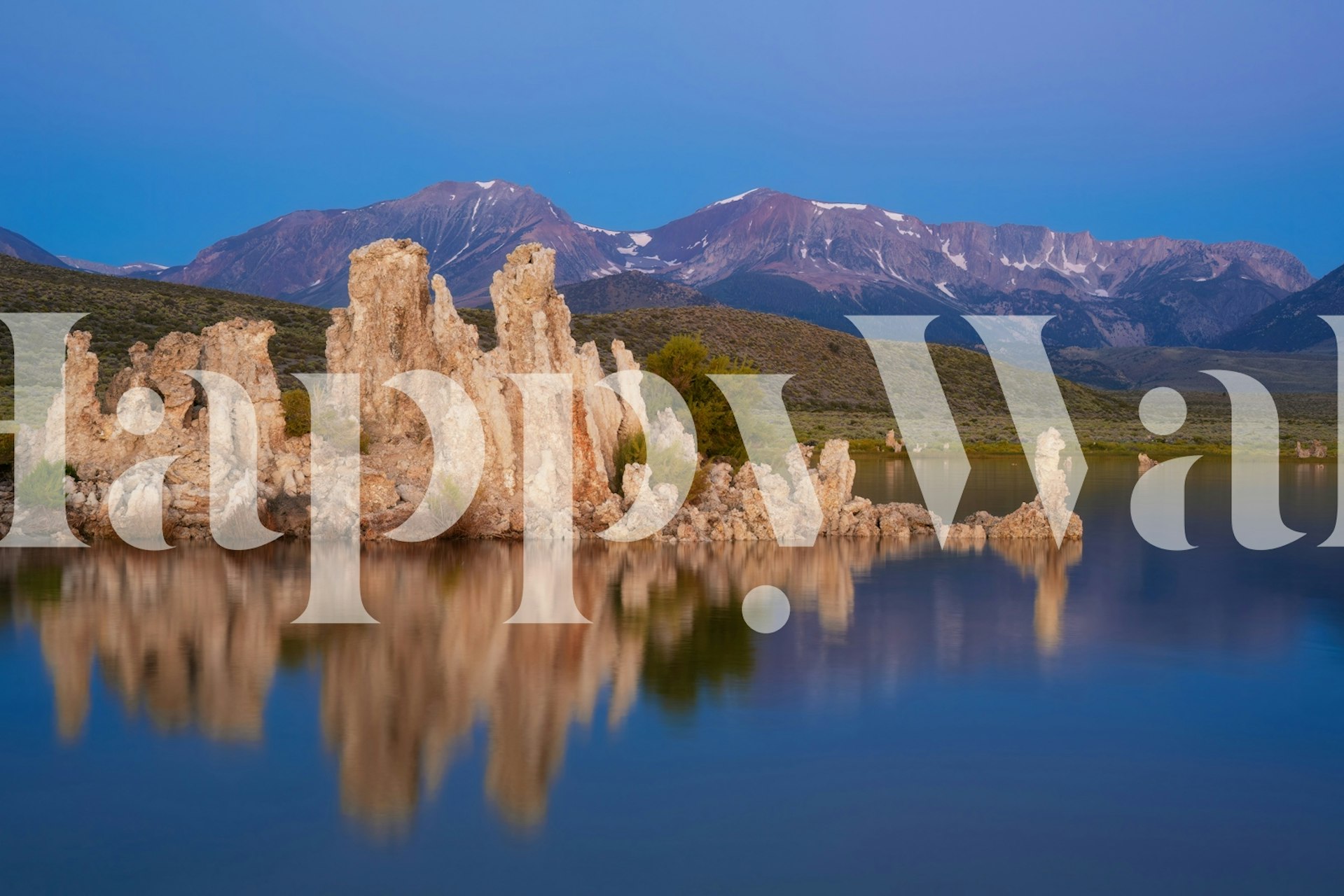 Calm water reflection of rocks and mountains in blue, green, and brown wallpaper