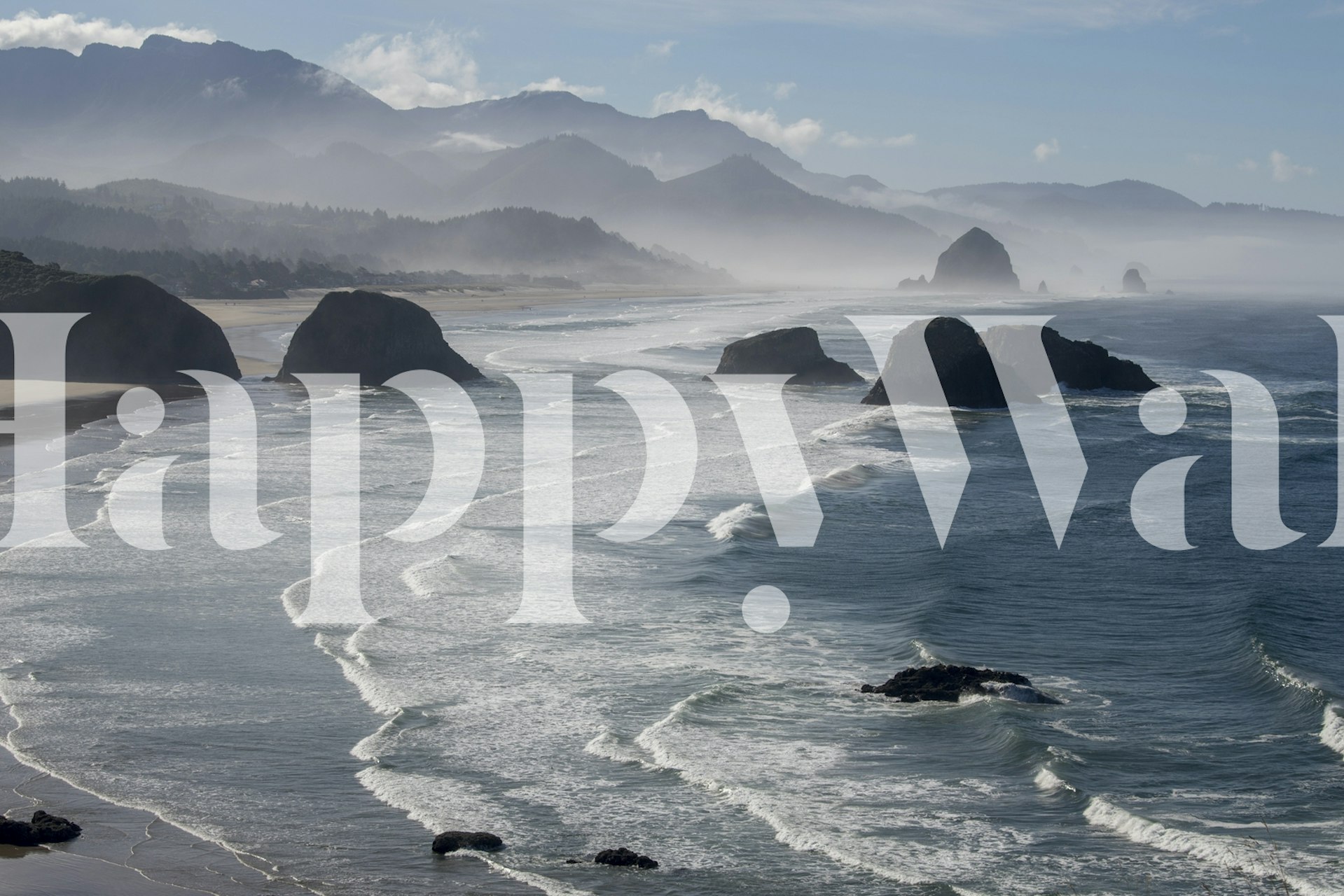 Ocean waves crashing on rocks under a misty sky wallpaper