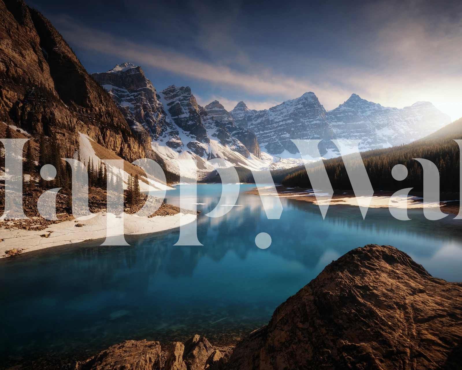 Mountain lake landscape with blue water, rocky shore, and snow-capped mountains wallpaper
