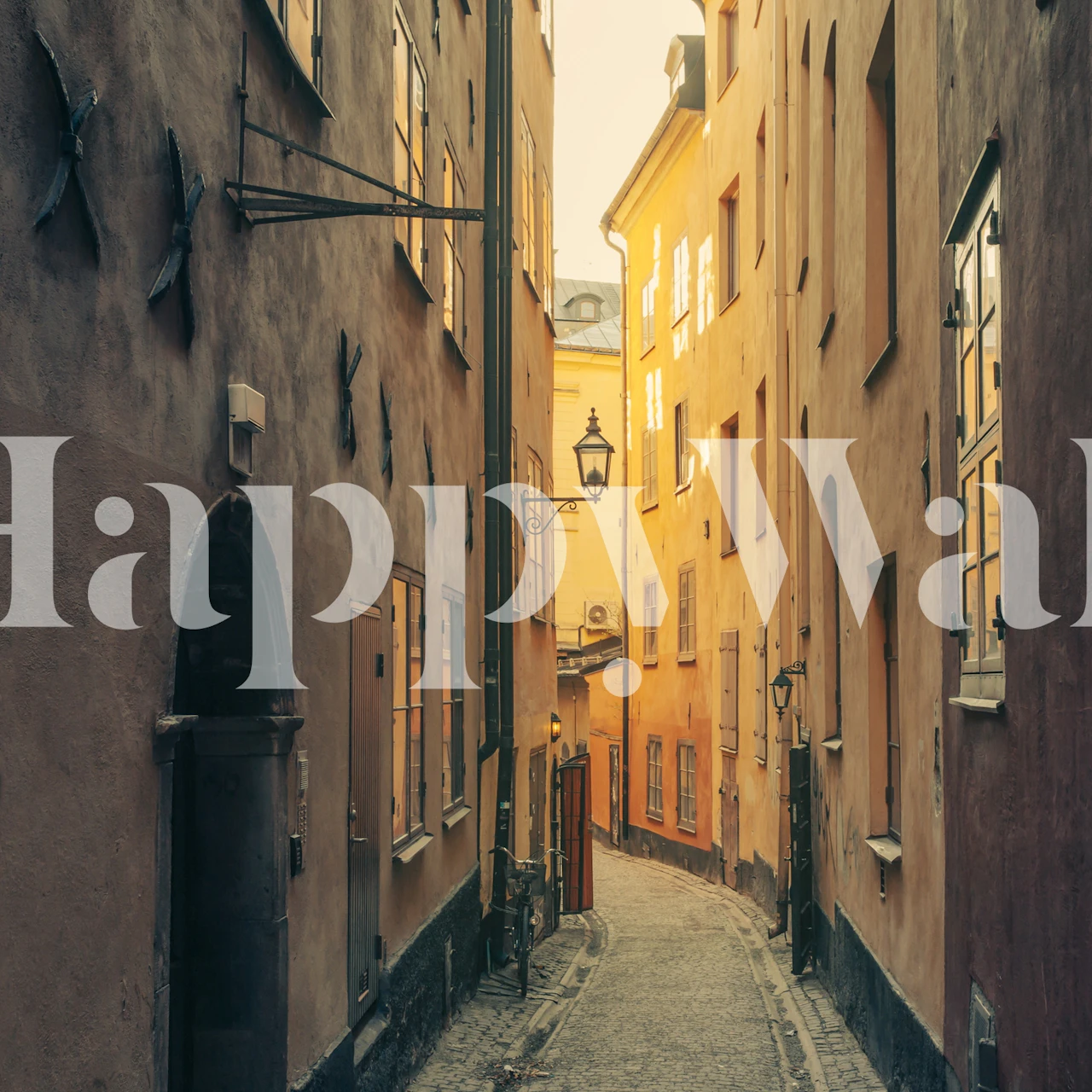 Narrow cobblestone street with warm yellow buildings wallpaper