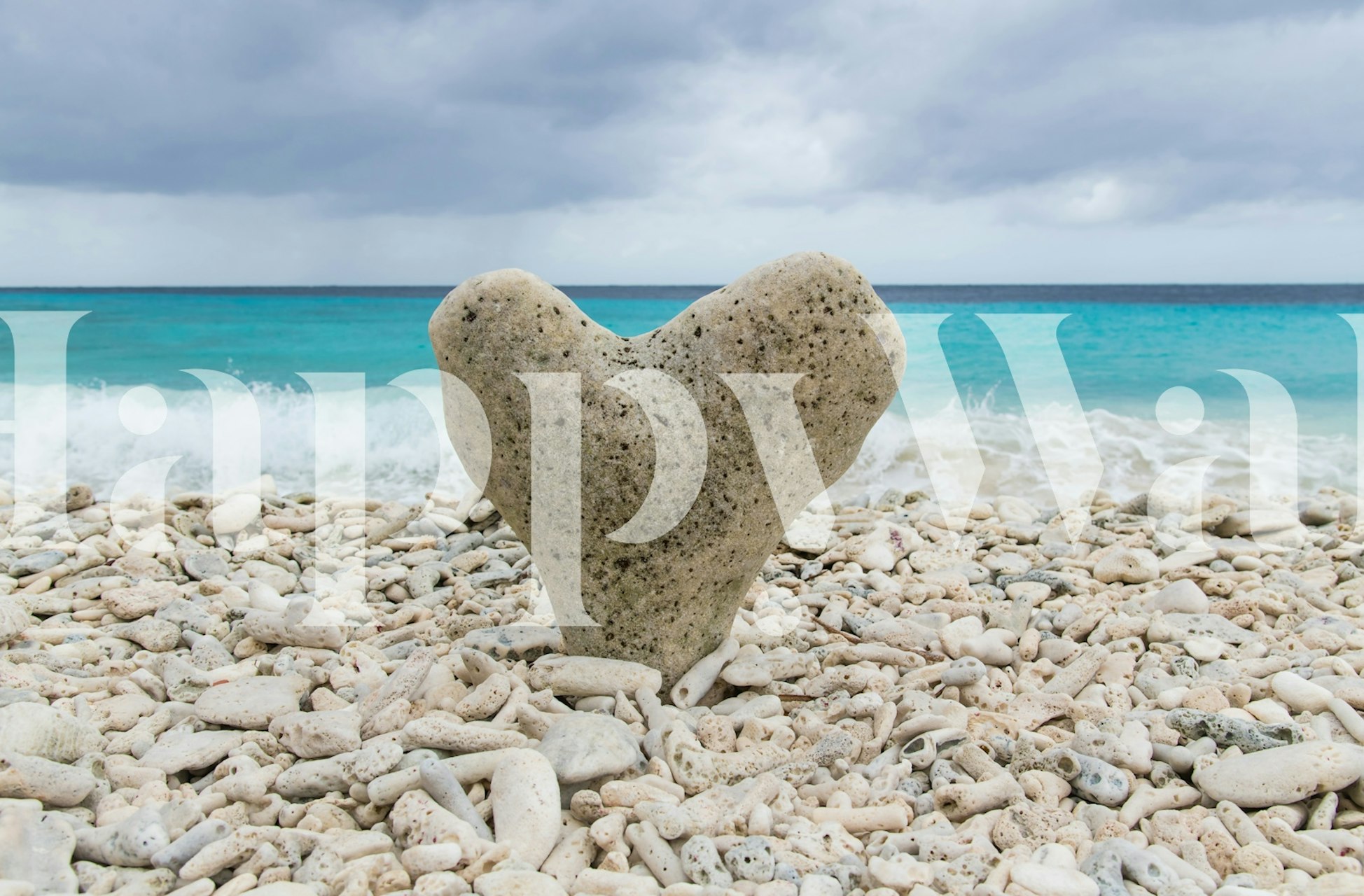 Heart-shaped stone on a pebbled beach with turquoise ocean backdrop wallpaper