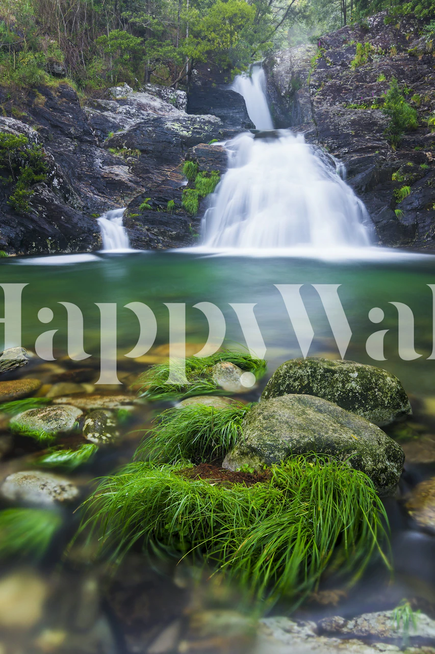 Emerald waterfall scene with green foliage and smooth stones wallpaper