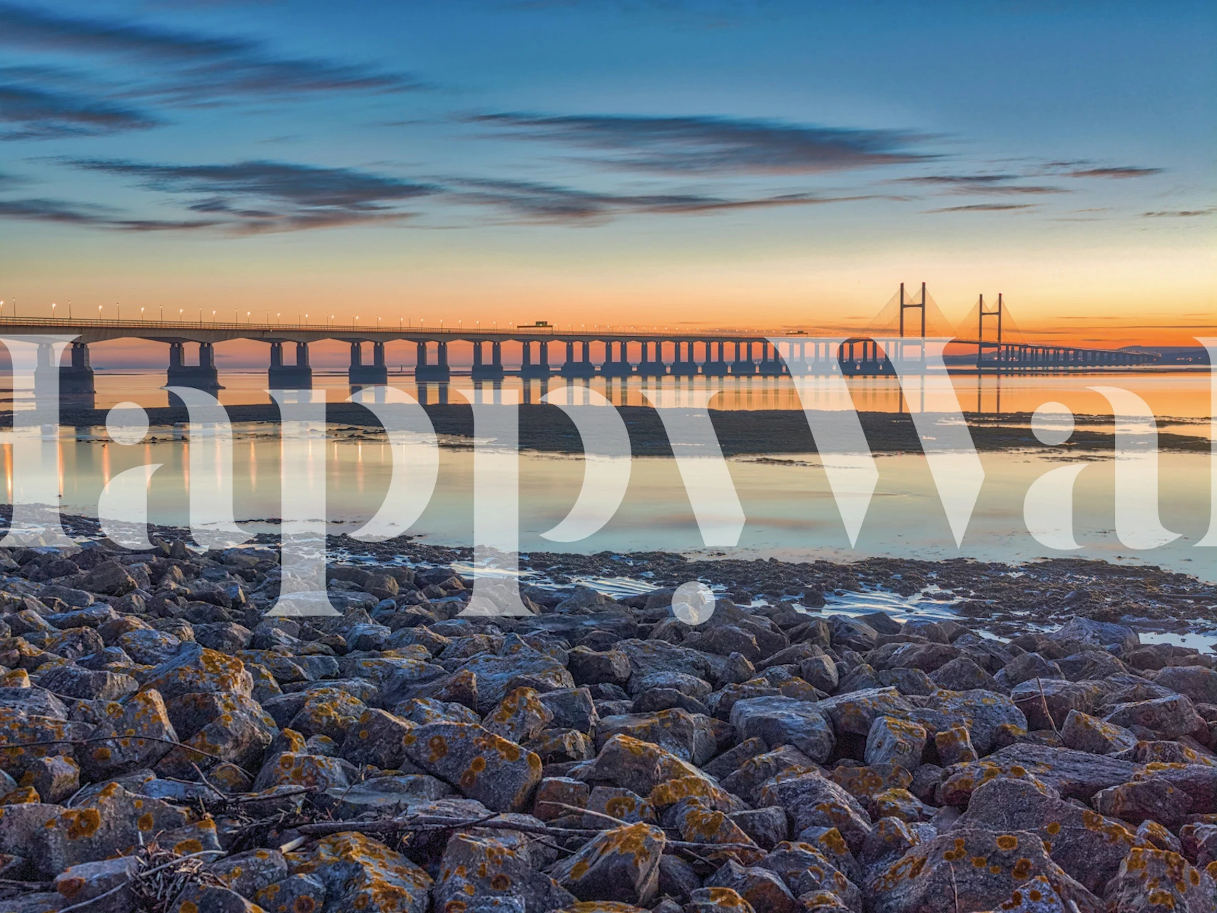 Scenic view of a river and bridge at sunset with rocky shore wallpaper