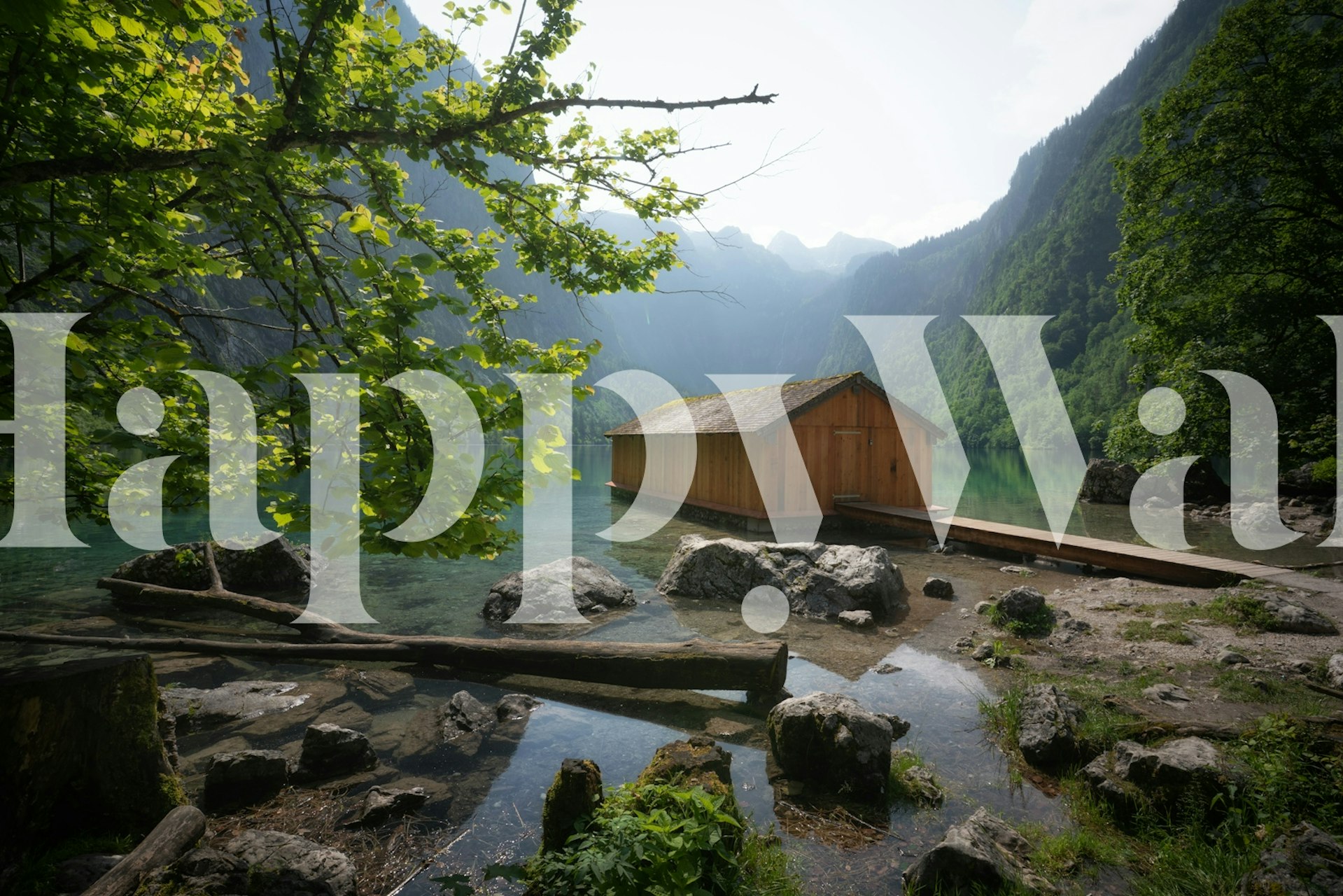 Wooden boathouse by a serene lake surrounded by mountains and greenery wallpaper