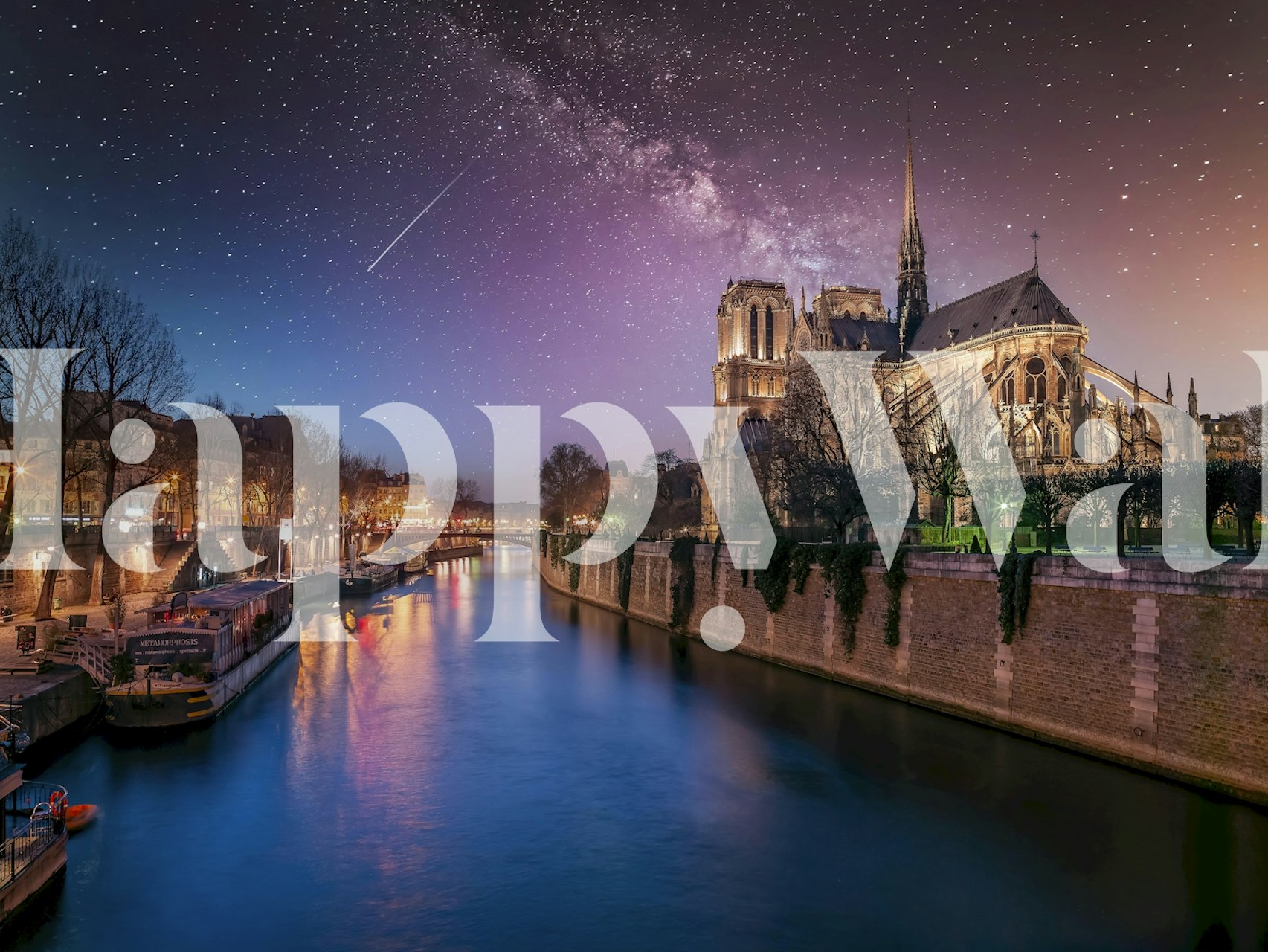Nighttime river scene with stars and illuminated buildings wallpaper