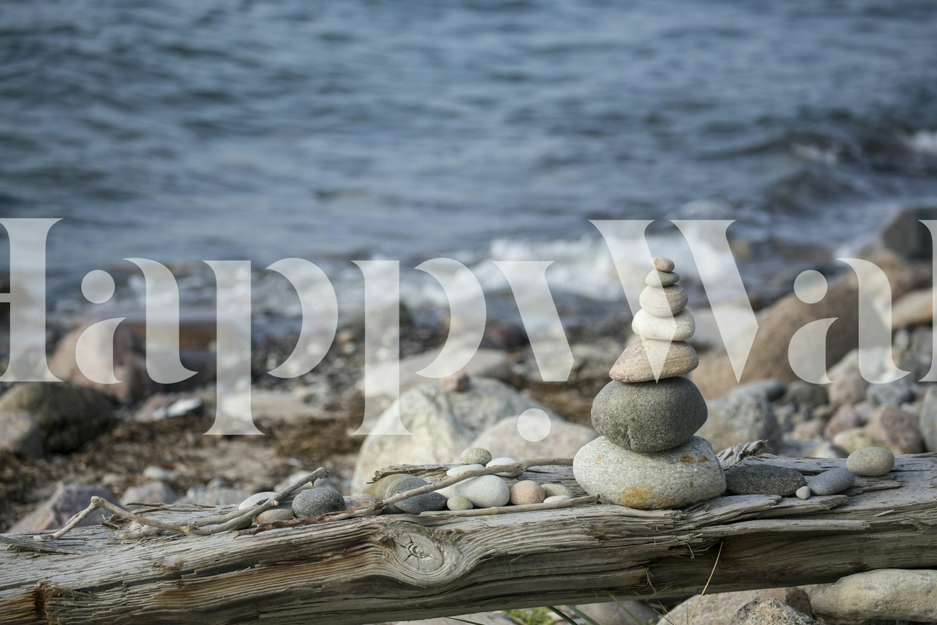 Stacked pebbles near the water's edge on a driftwood log wallpaper