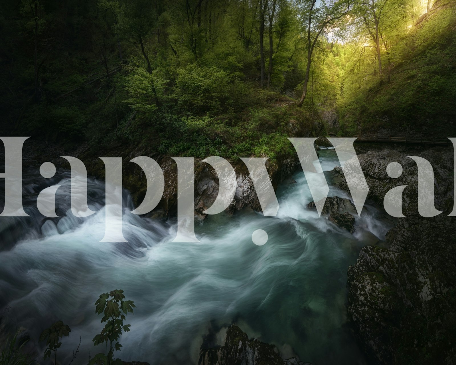 Lush green river flowing through rocks and trees wallpaper