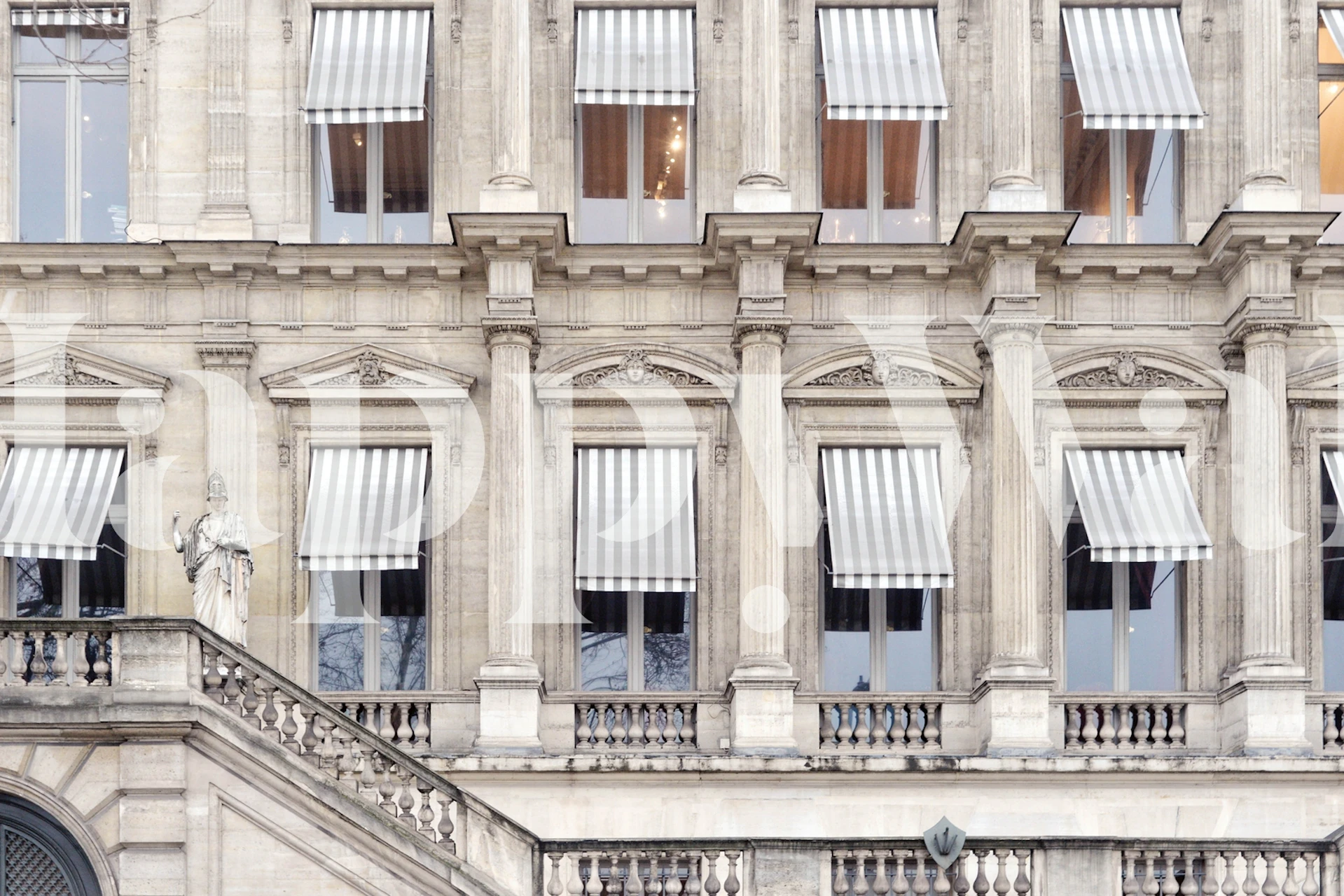 Classic Parisian building with stone walls, windows, and striped awnings wallpaper