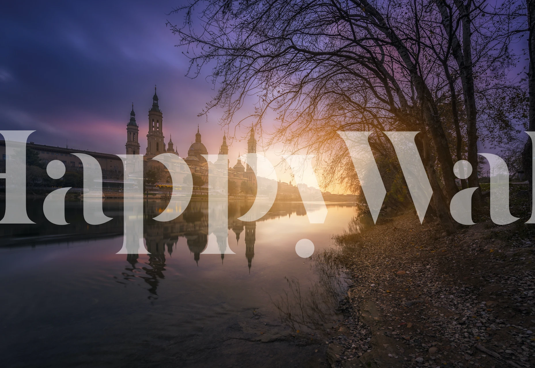 Sunset over a river with trees and buildings reflecting on water, landscape wallpaper