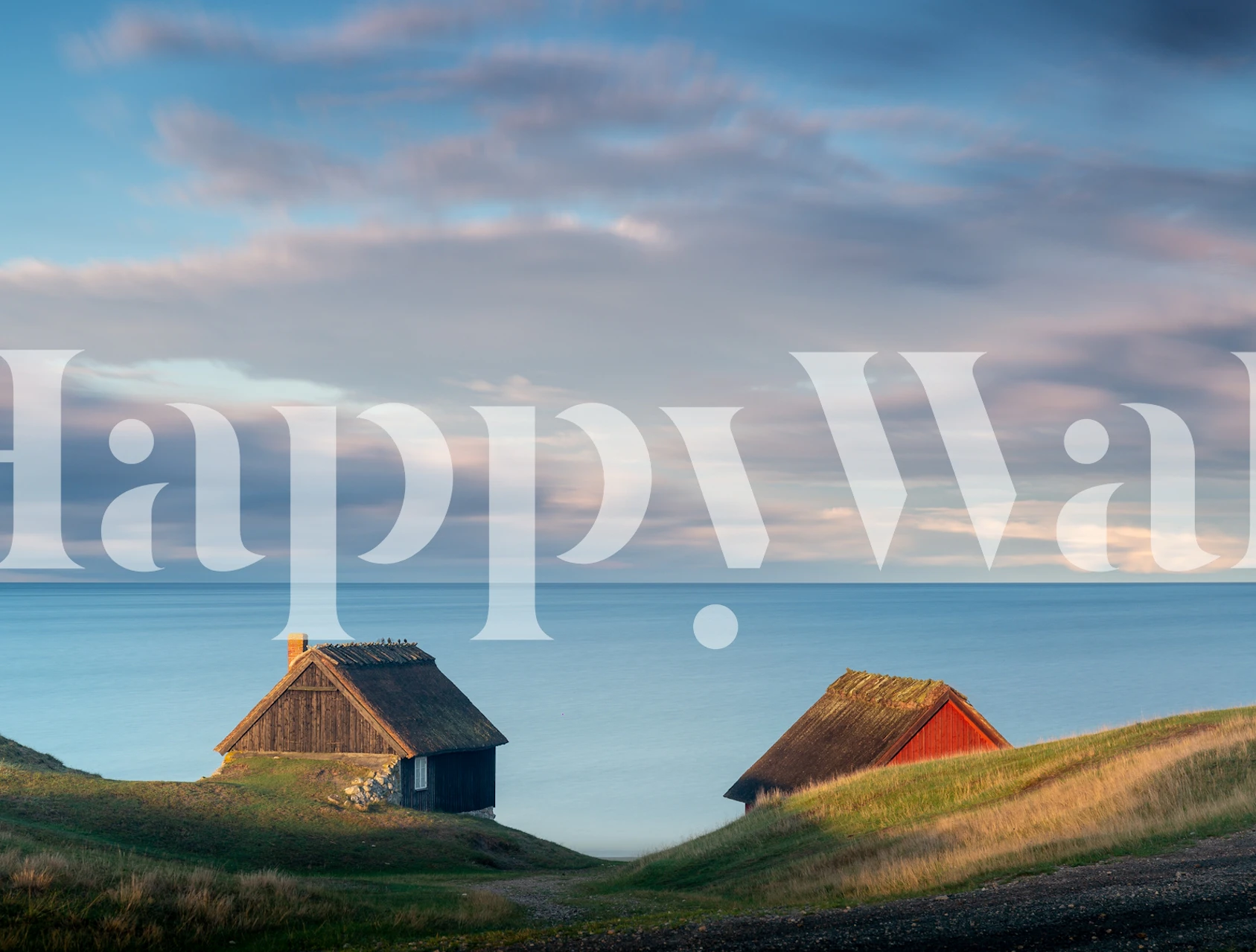 Two rustic cabins on green hills with ocean in background, blue tones wallpaper