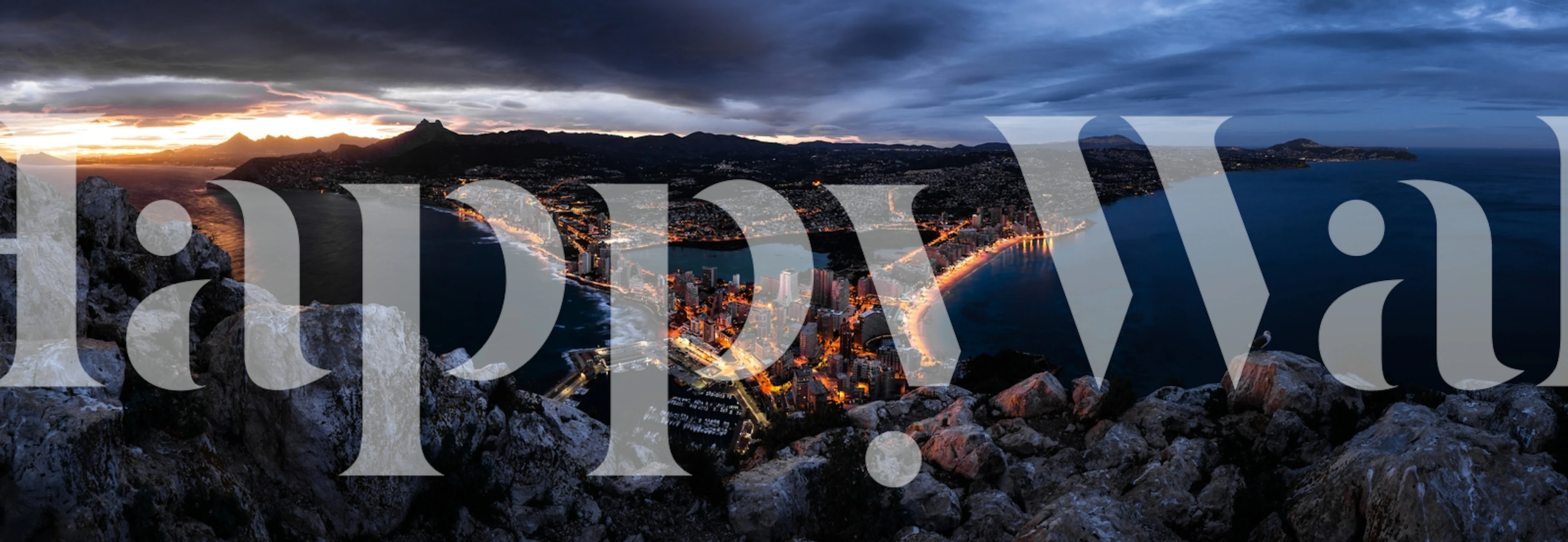 Coastal town panoramic wall mural depicting Calp after sunset with twinkling town lights and a tranquil sea.