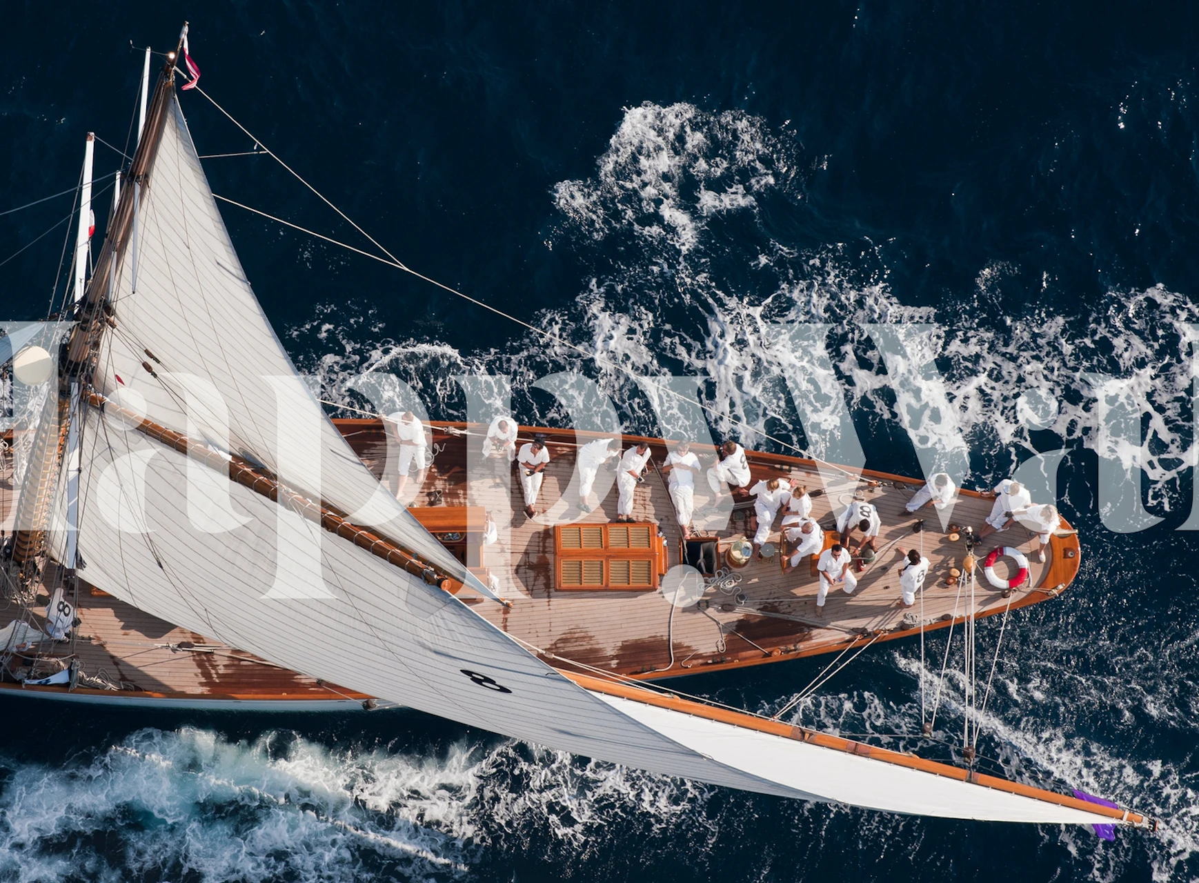 Sailboat on ocean waves with crew in white attire wallpaper