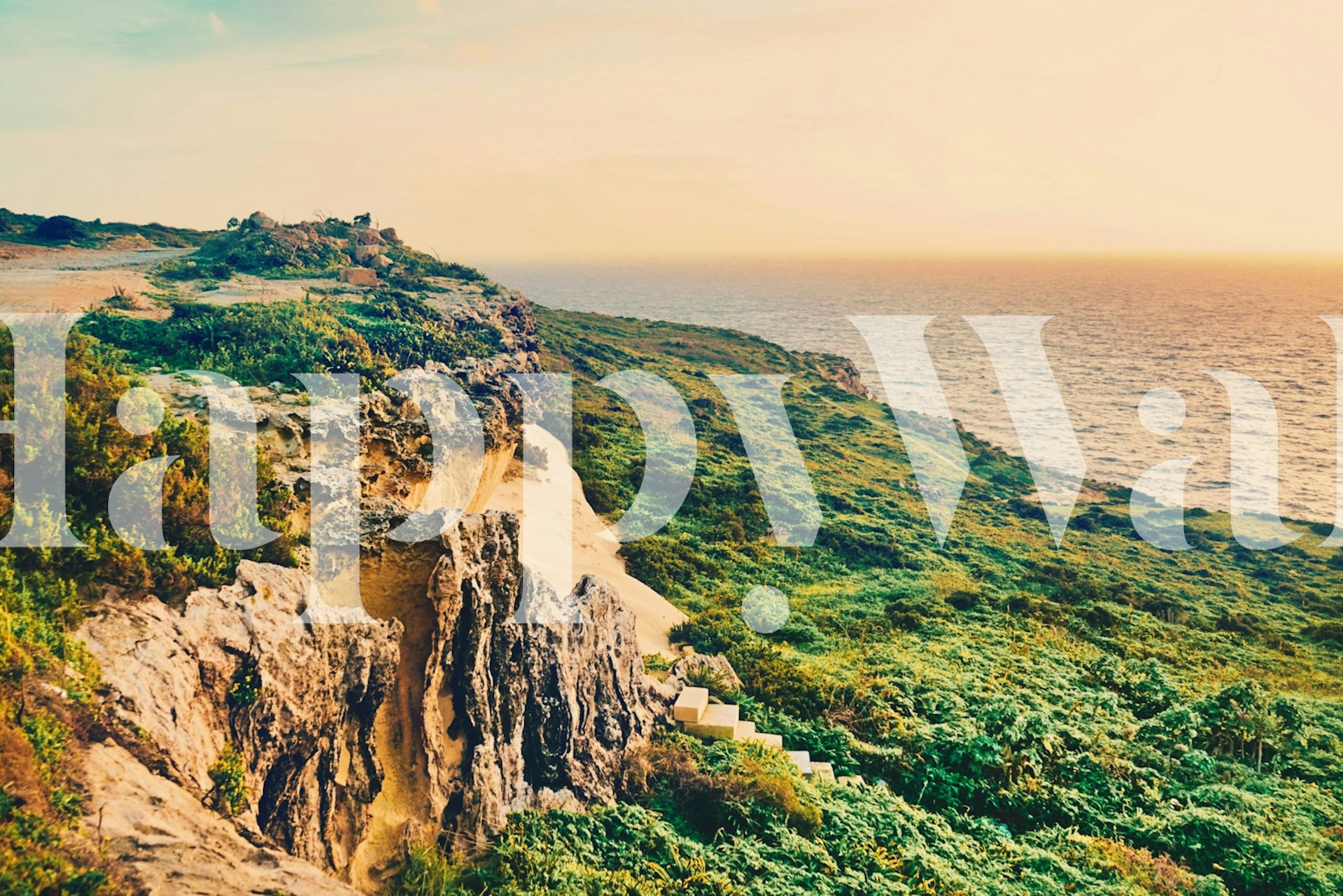 Carta da parati Ocean Sunset raffigurante il sole che tramonta su un paesaggio costiero con scogliere e vegetazione lussureggiante