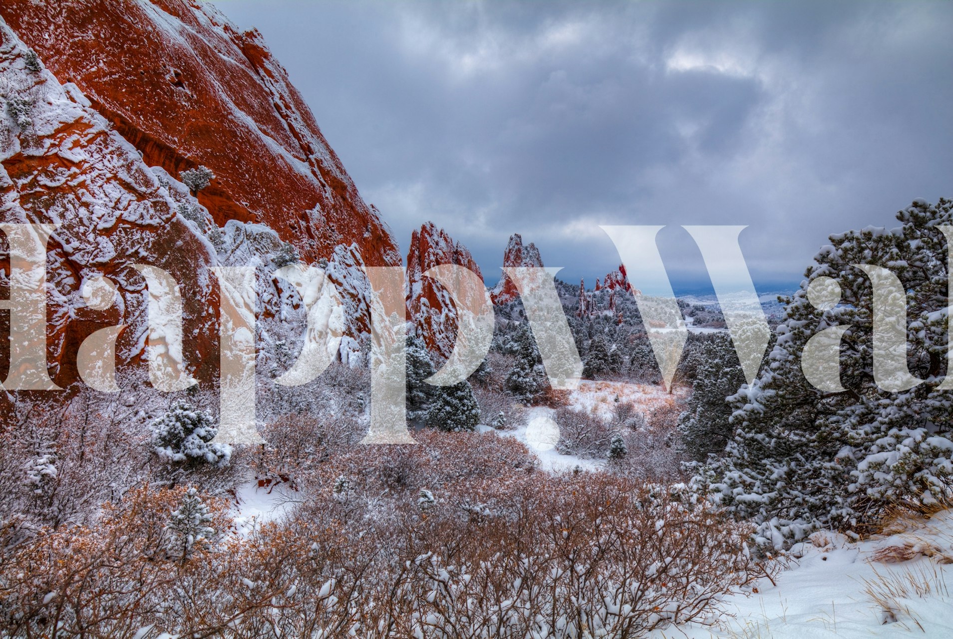 Snow-covered red rock landscape with trees and gray sky wallpaper