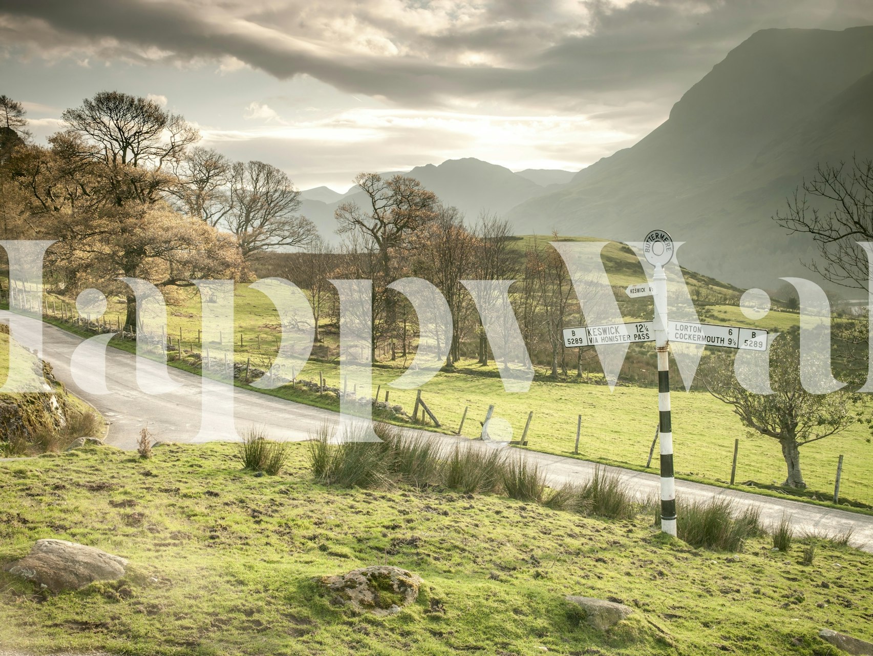 Countryside road leading through green pastures and mountains wallpaper