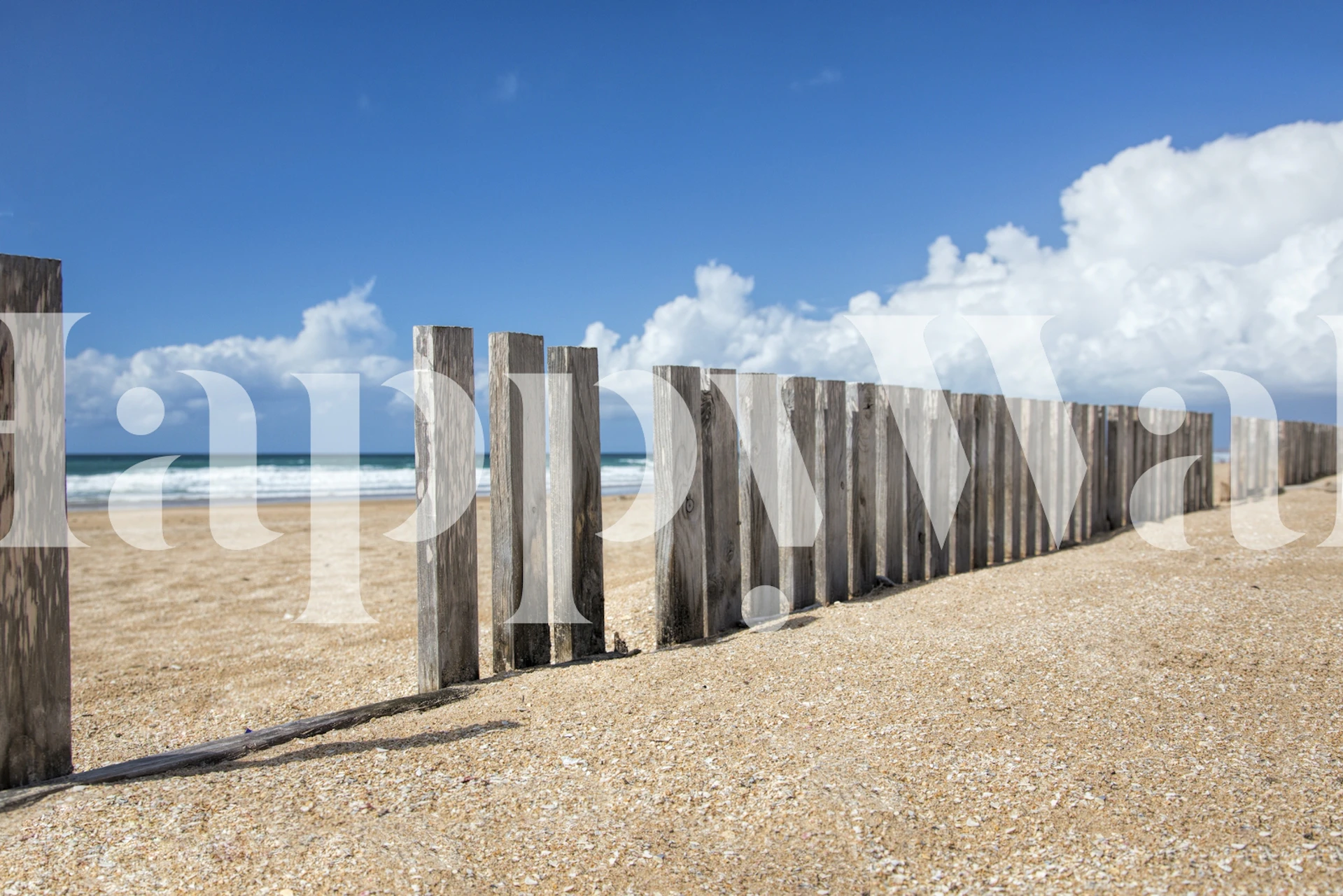 Wooden fence along a sandy beach with blue ocean wallpaper