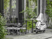 Scooter parked by street cafe behang