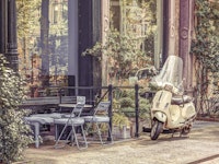 Scooter parked by street cafe 4 behang