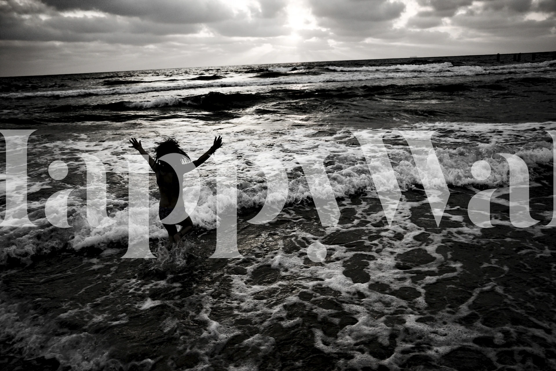 Person jumping in the ocean with waves crashing around, black and white wallpaper