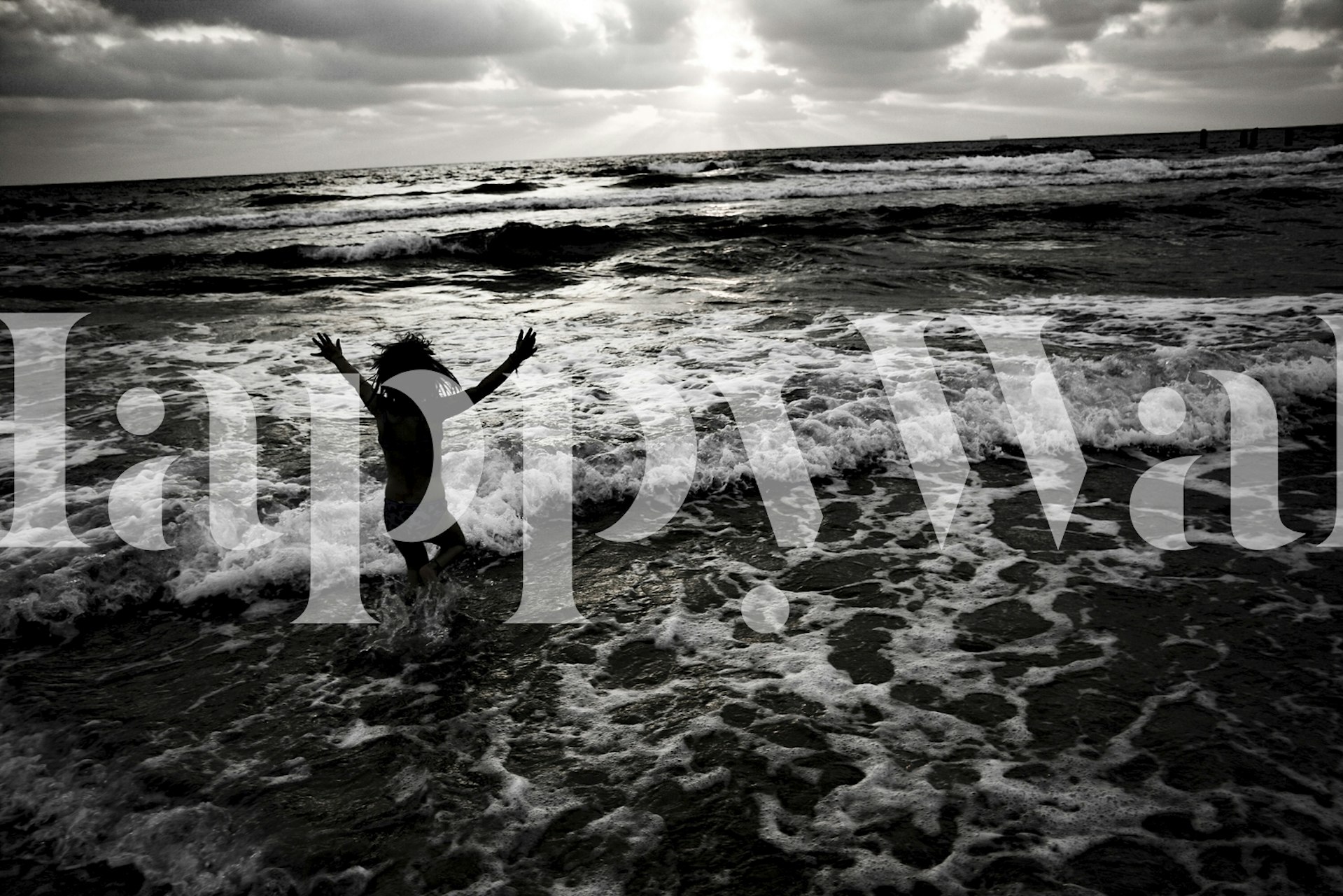 Person jumping in the ocean with waves crashing around, black and white wallpaper