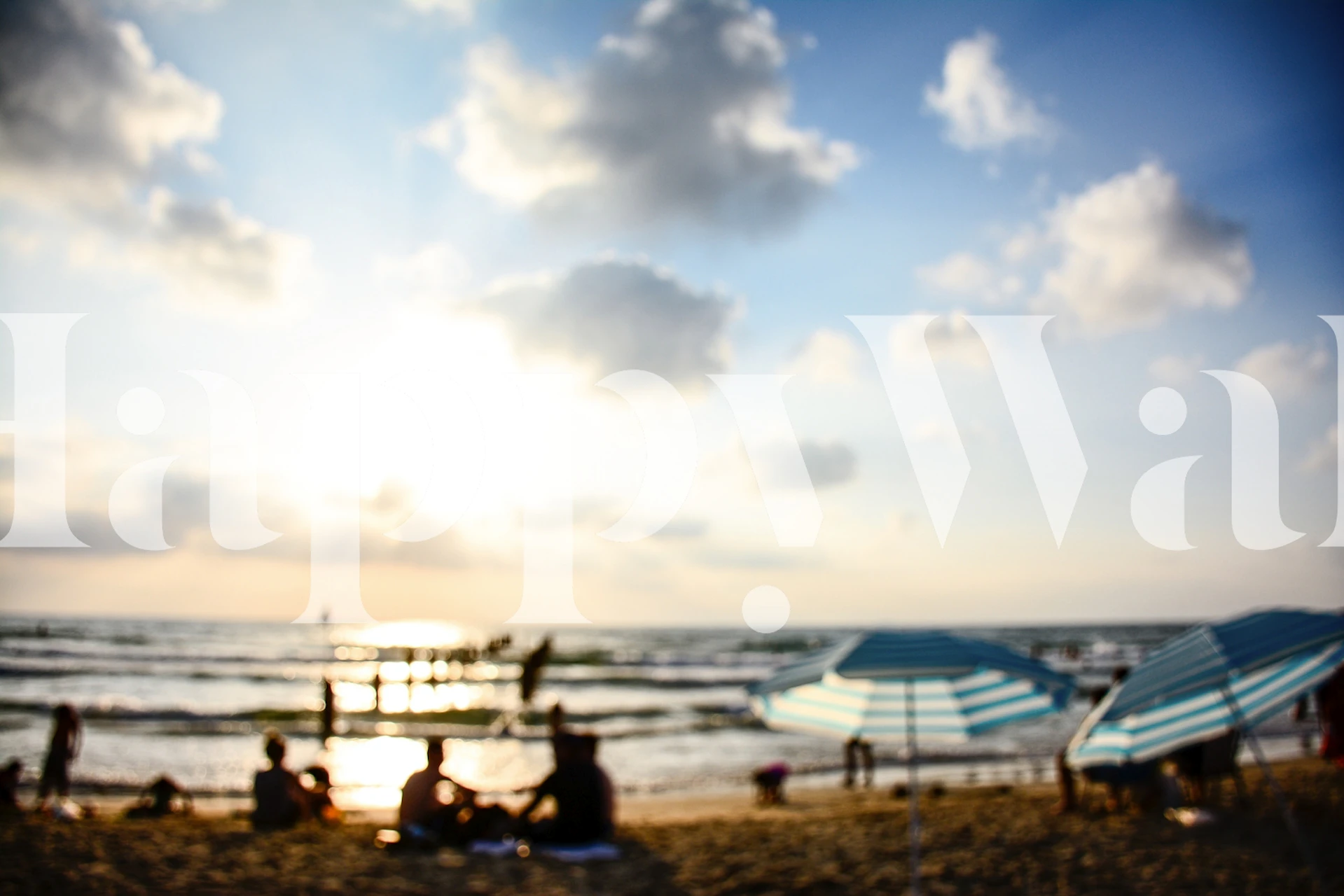 Late afternoon scenery at the beach with silhouettes of people and umbrellas