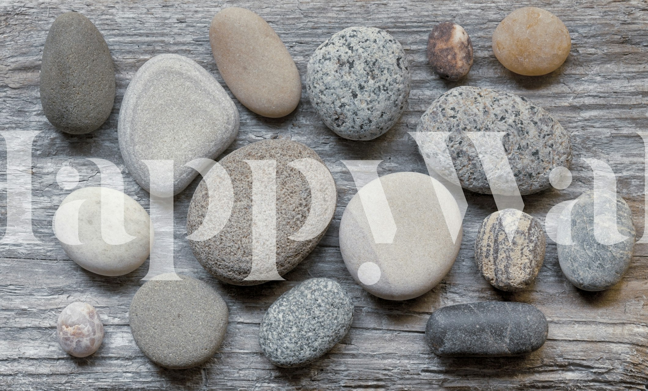 Grey pebbles of various shapes and sizes on textured wood wallpaper