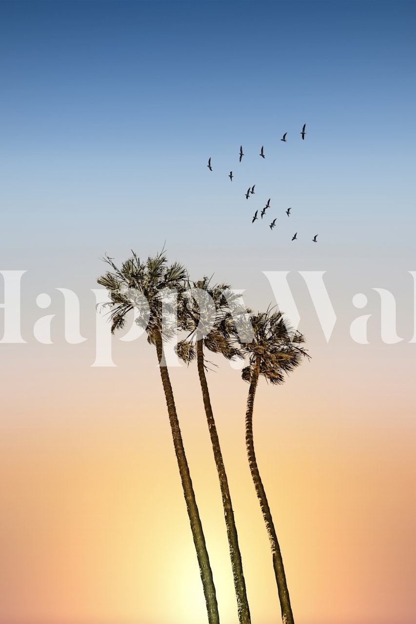 Silhouette di palme contro un murale al tramonto con uccelli in volo