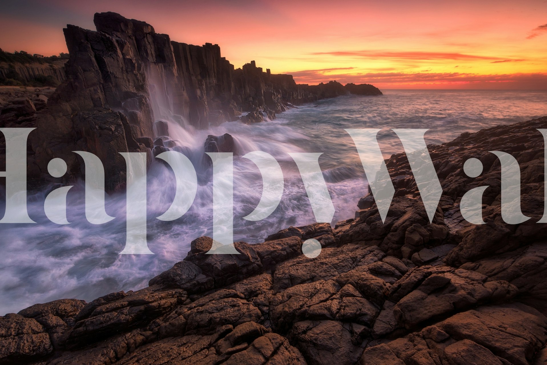 Sunset at a rugged coastline wall mural with waves crashing into rocks