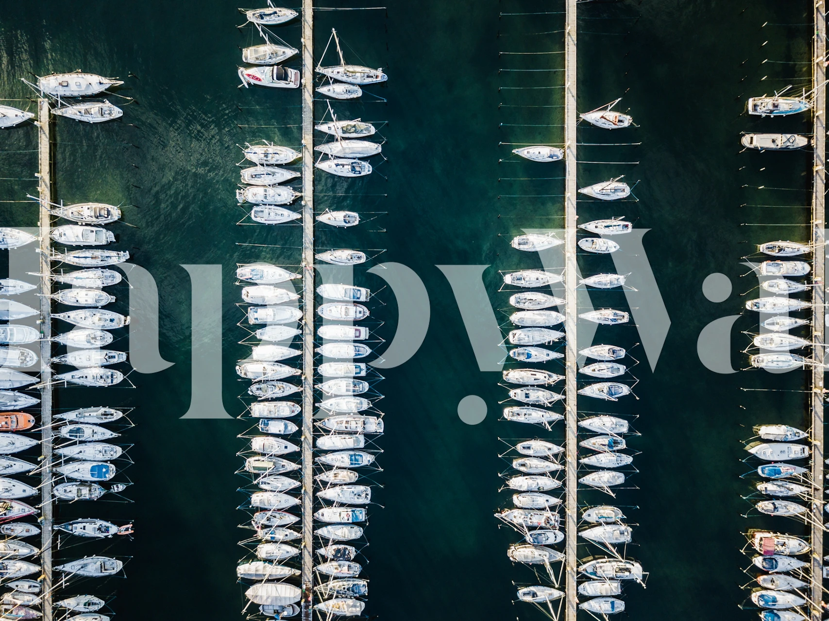 Aerial view of a boat dock with numerous boats in different colors on dark water wallpaper