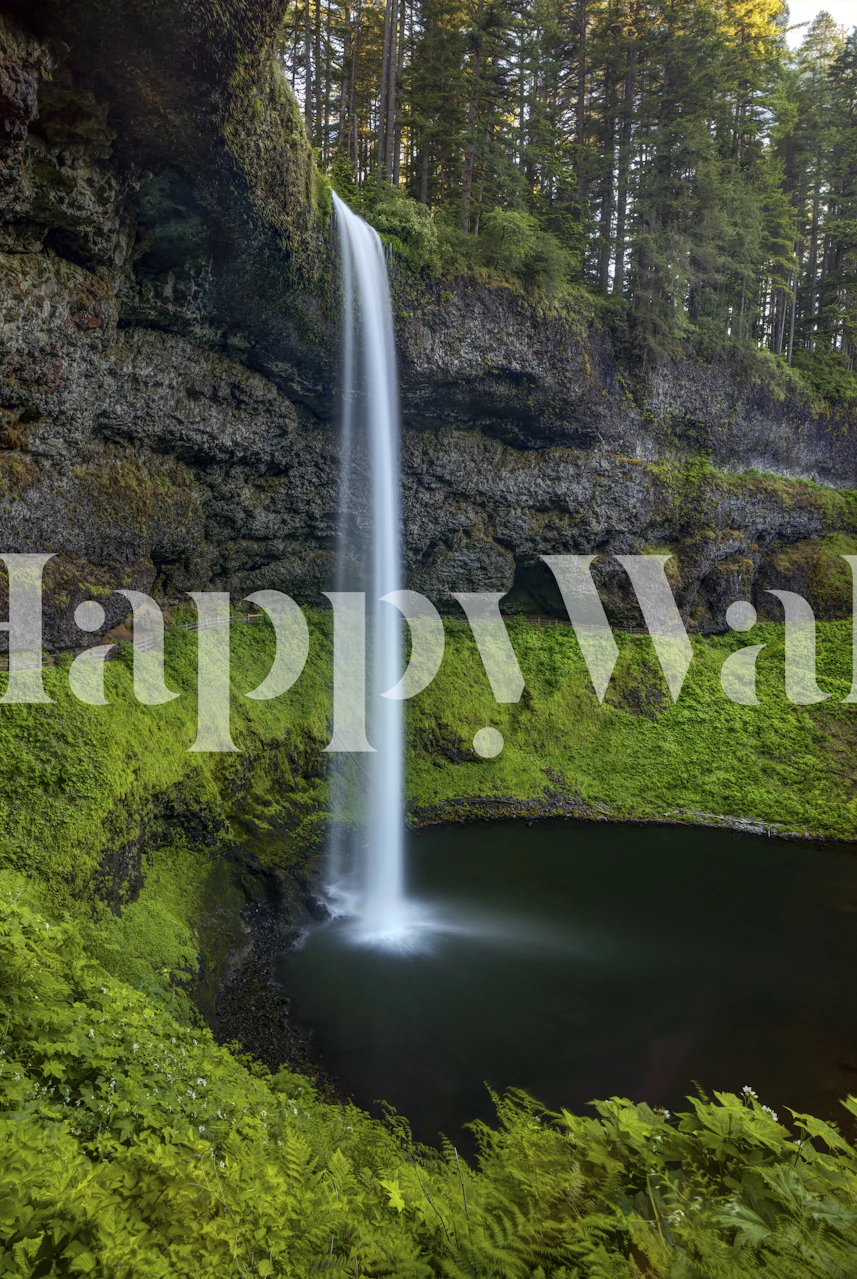 Waterfall surrounded by green foliage and rocky cliffs wallpaper
