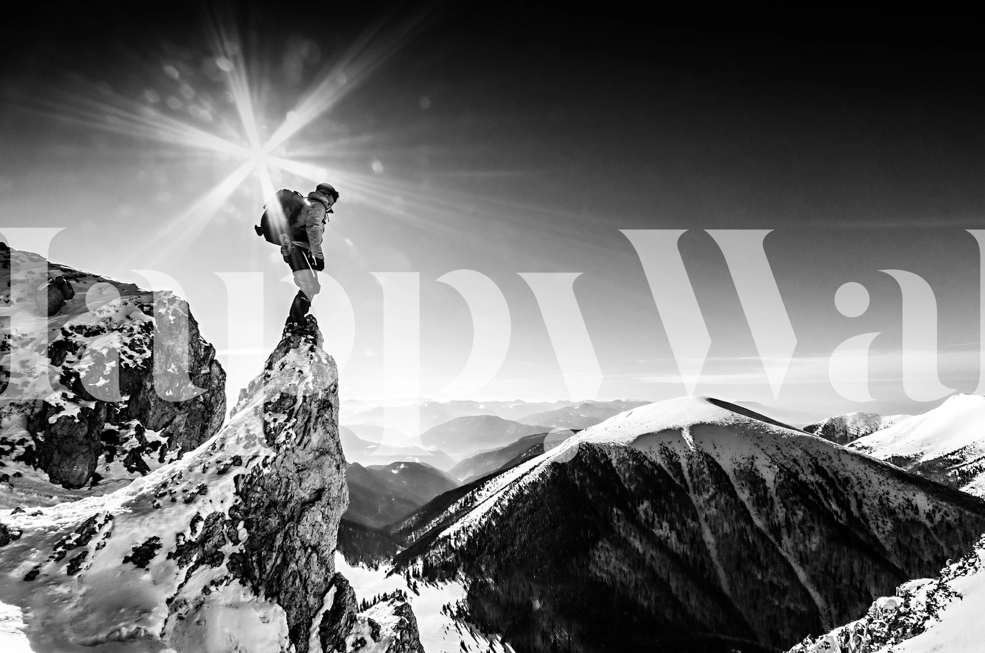 A climber on a snowy mountain peak under a bright sunburst black and white wallpaper