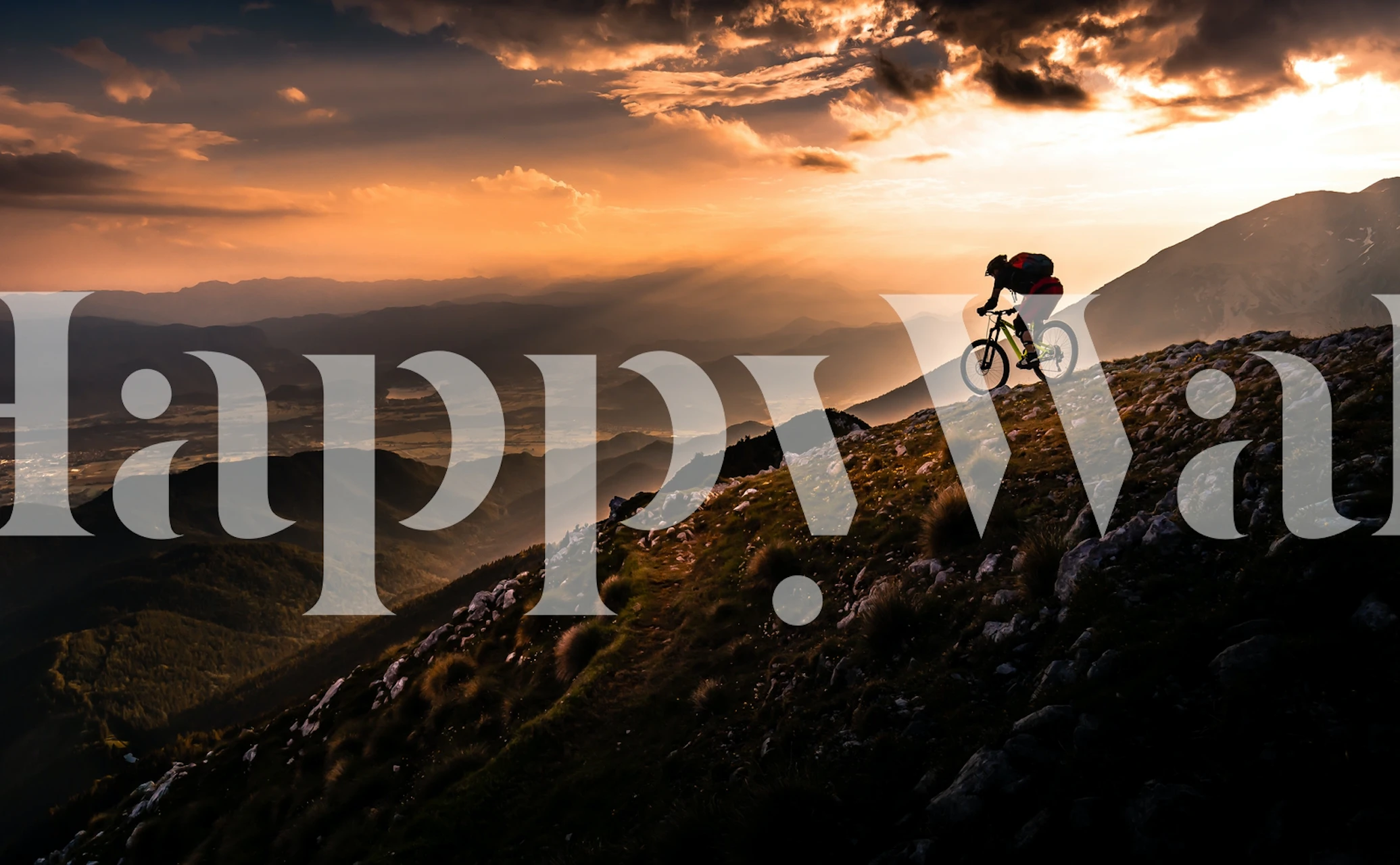 Silhouette of a cyclist on a mountain at sunset with orange and purple hues wallpaper