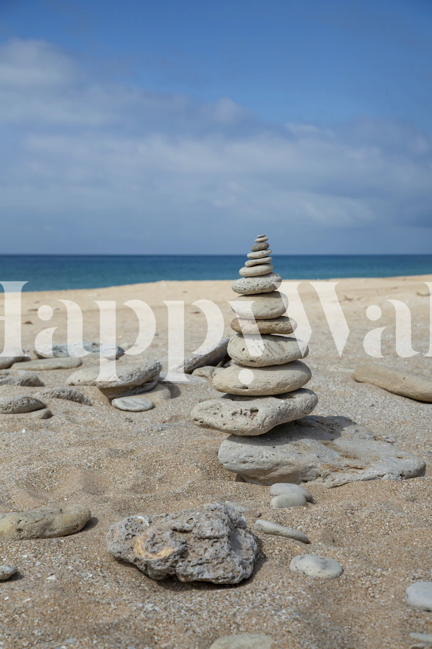 Cairn of stacked stones on sandy beach with ocean view wallpaper