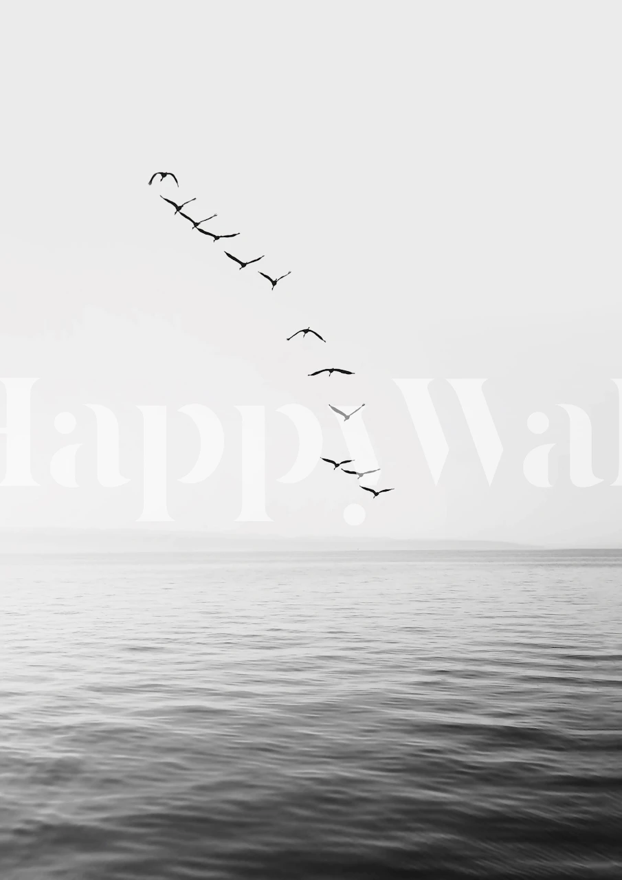 Un sereno mural en blanco y negro de pájaros volando sobre el mar.