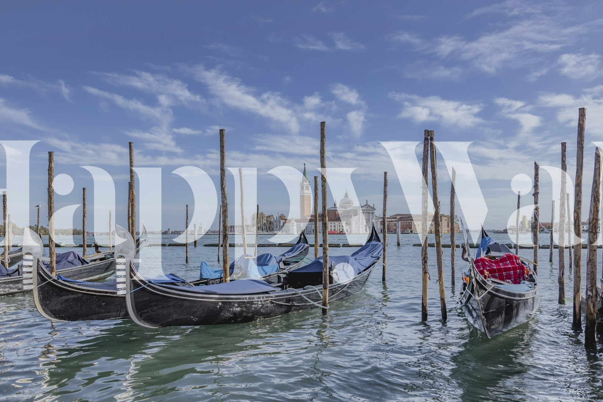 Gondolas on blue water with wooden poles and buildings in the background wallpaper