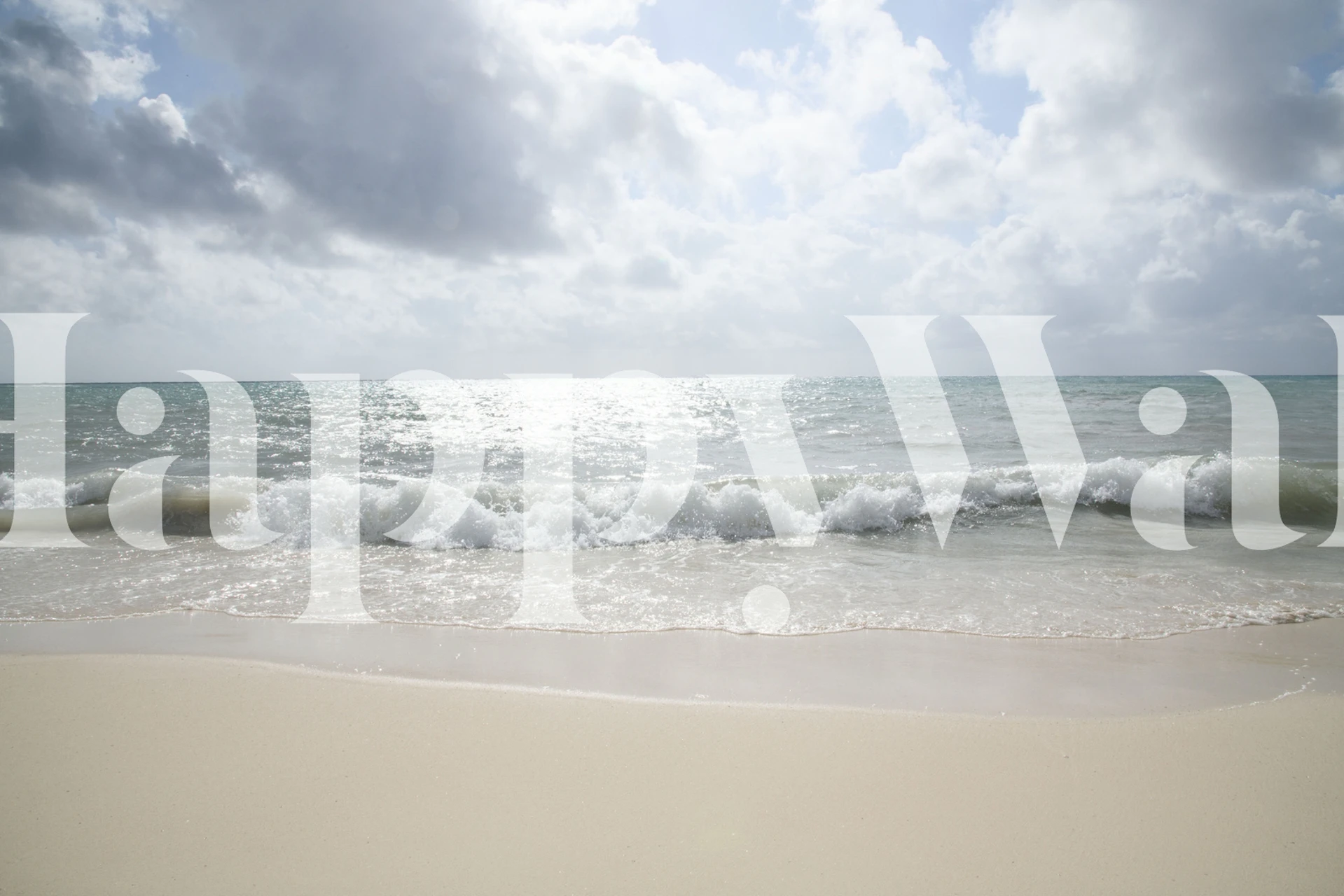 Caribbean beach with foamy waves and golden sand under a cloudy sky