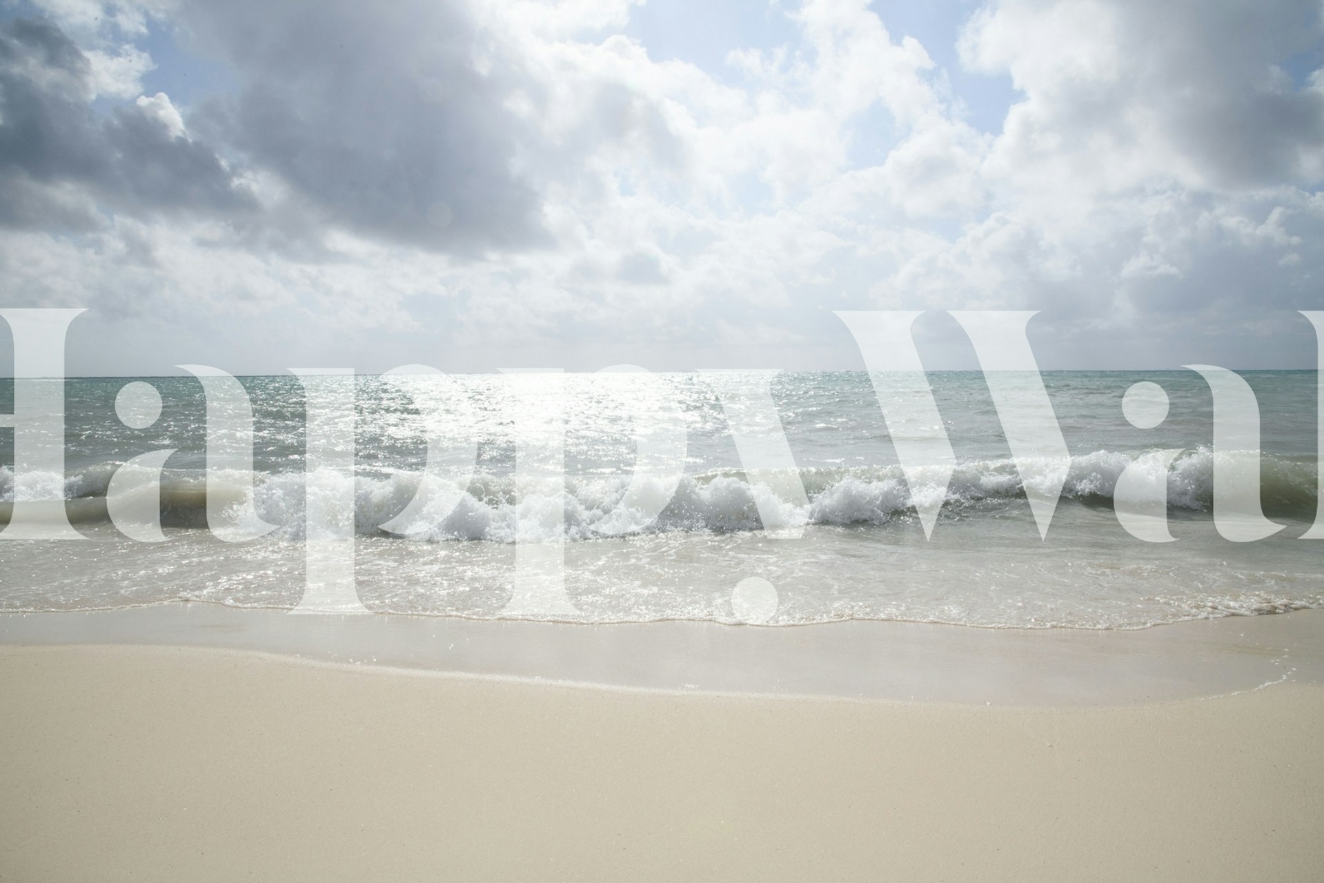 Caribbean beach with foamy waves and golden sand under a cloudy sky