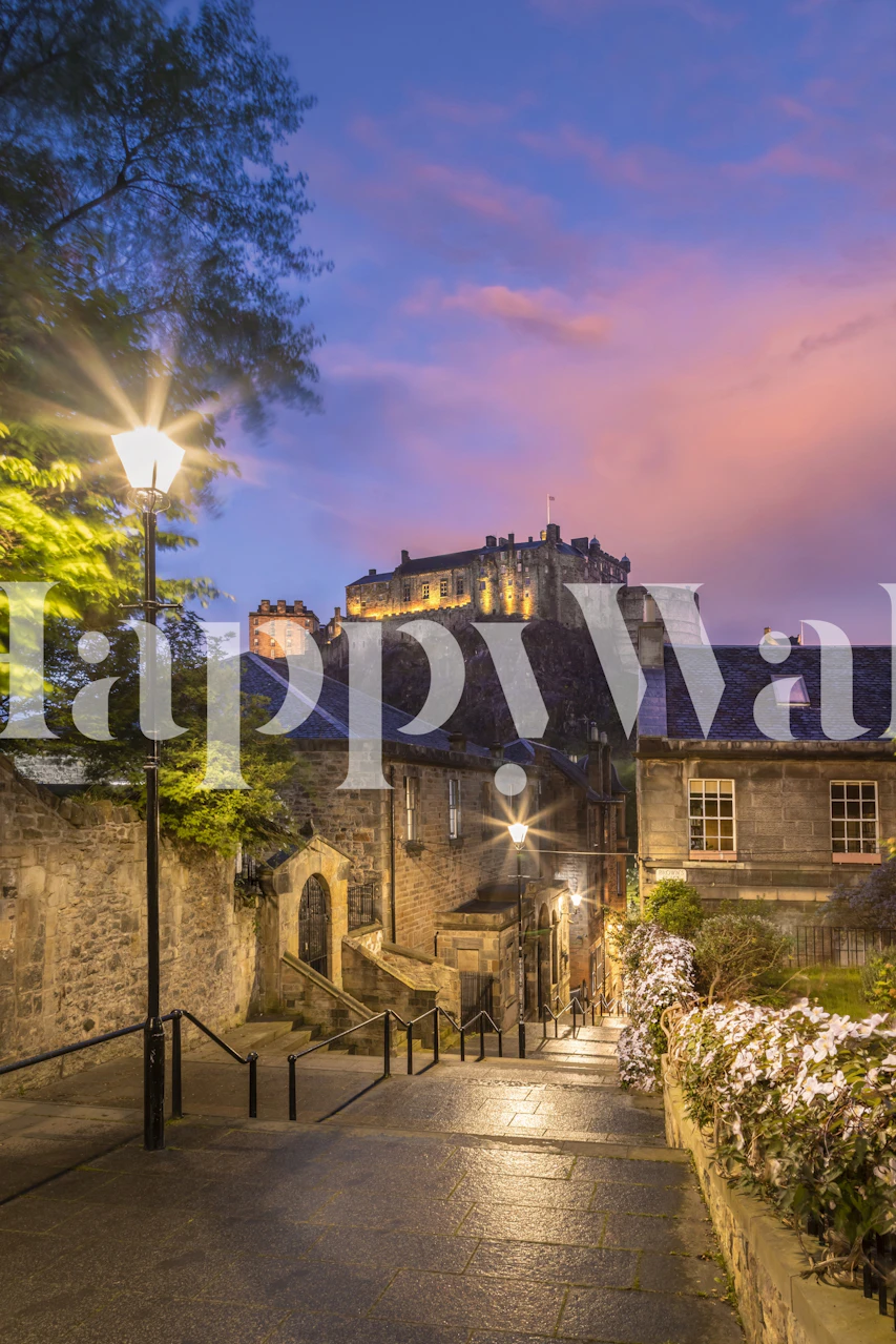 Edinburgh Castle at sunset with street lights and blooming flowers along a cobblestone path