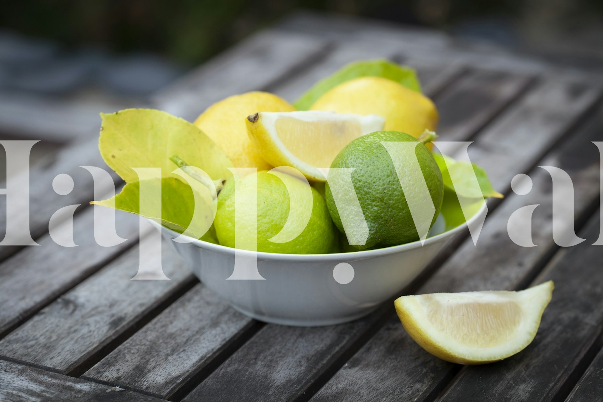 Mísa čerstvých citronů a limetek na fototapetu dřevěný stůl