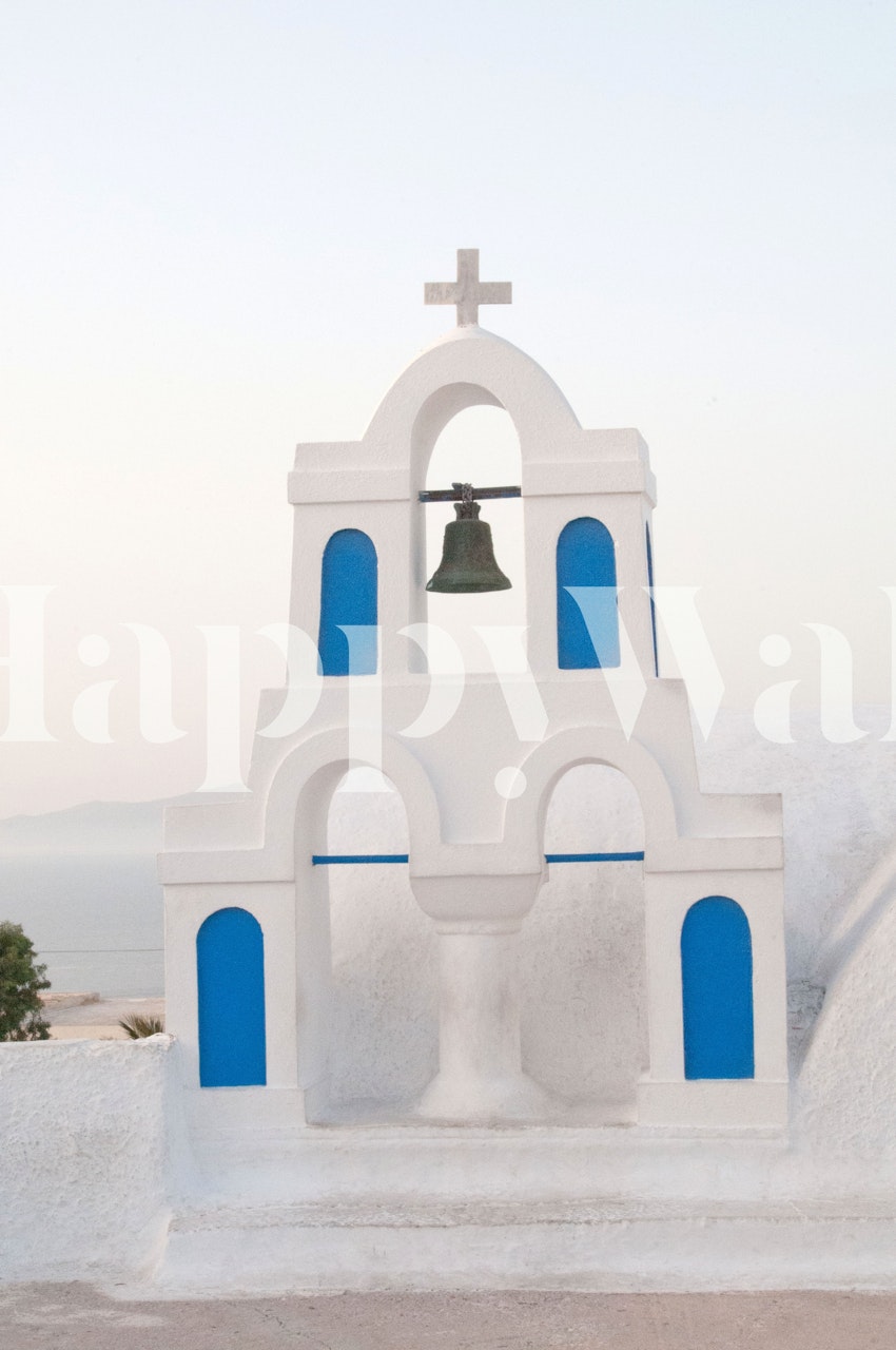 Řecká zvonice s bílými stěnami a modrými akcenty pod nástěnnou malbou s jasnou oblohou