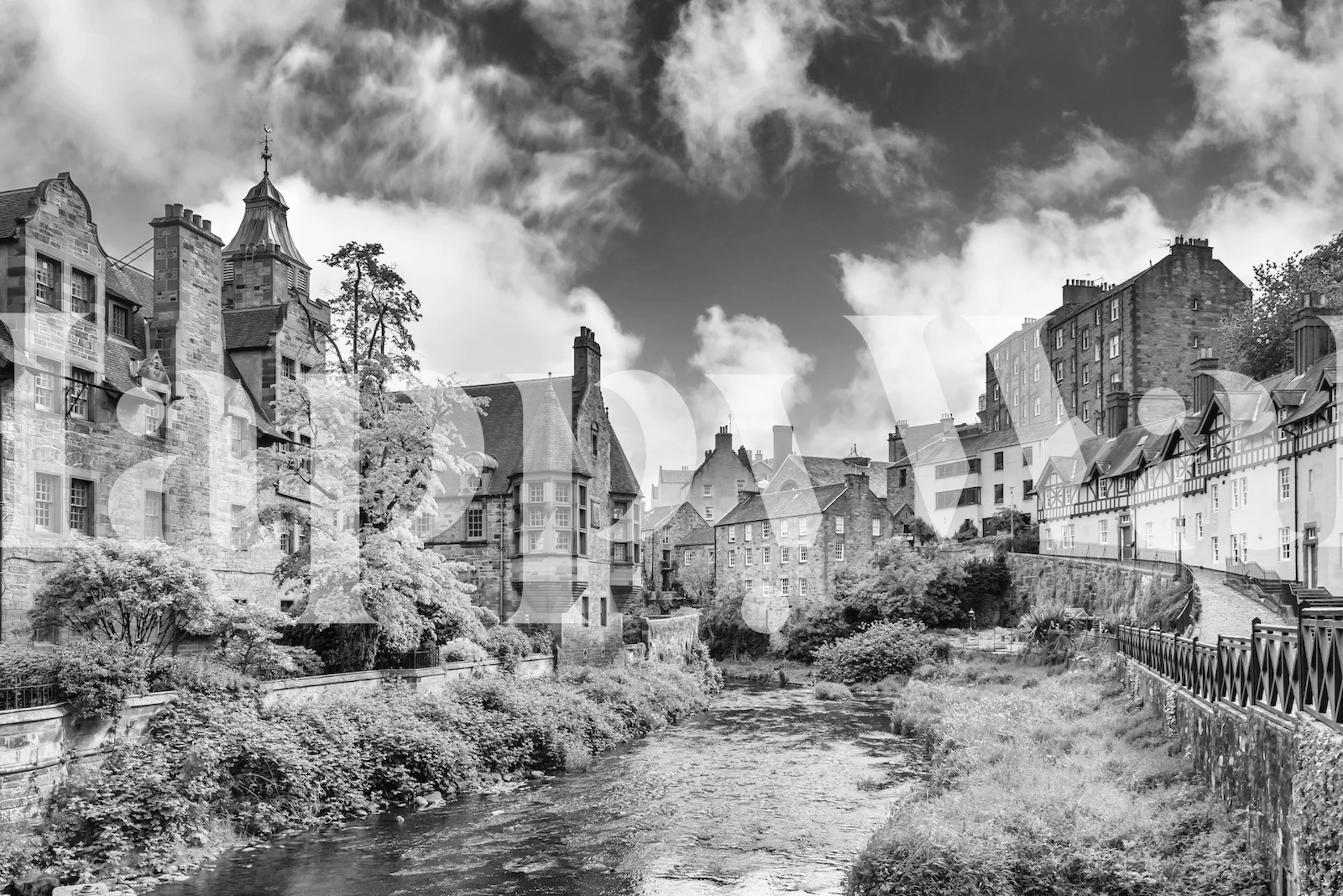 Svart-hvitt veggmaleri av Edinburghs historiske Dean Village med steinbygninger og en rolig elv.