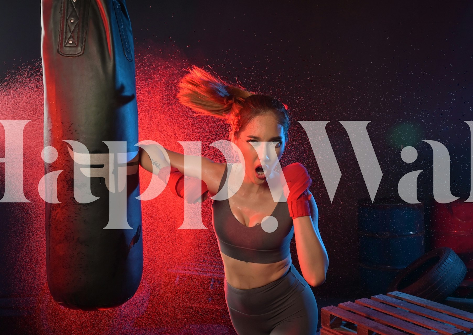Dynamic woman boxer in red gloves with punching bag wallpaper