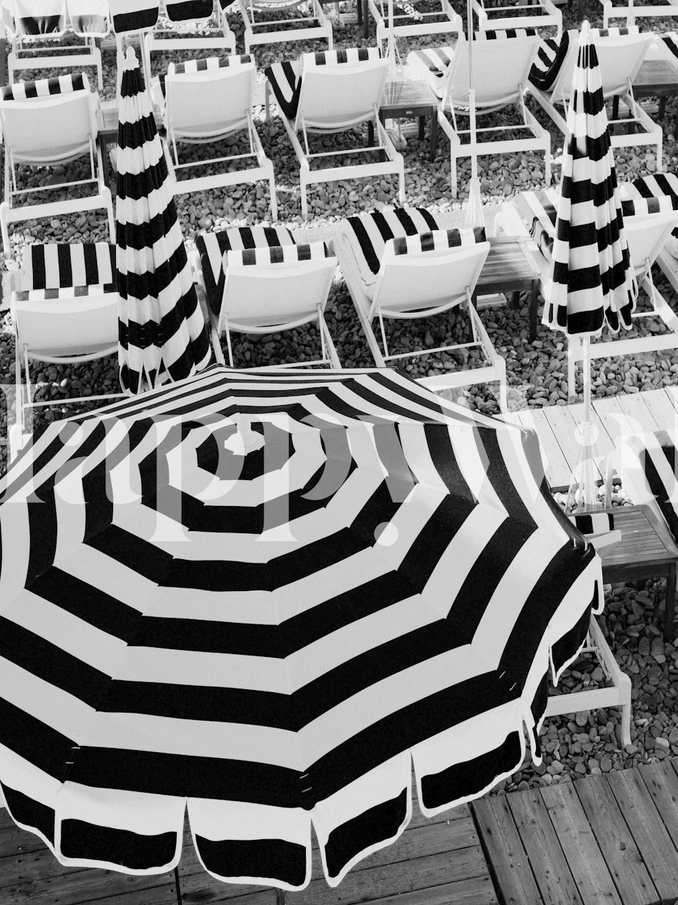 Monochrome wall mural featuring beach umbrellas and chairs in a striped pattern.