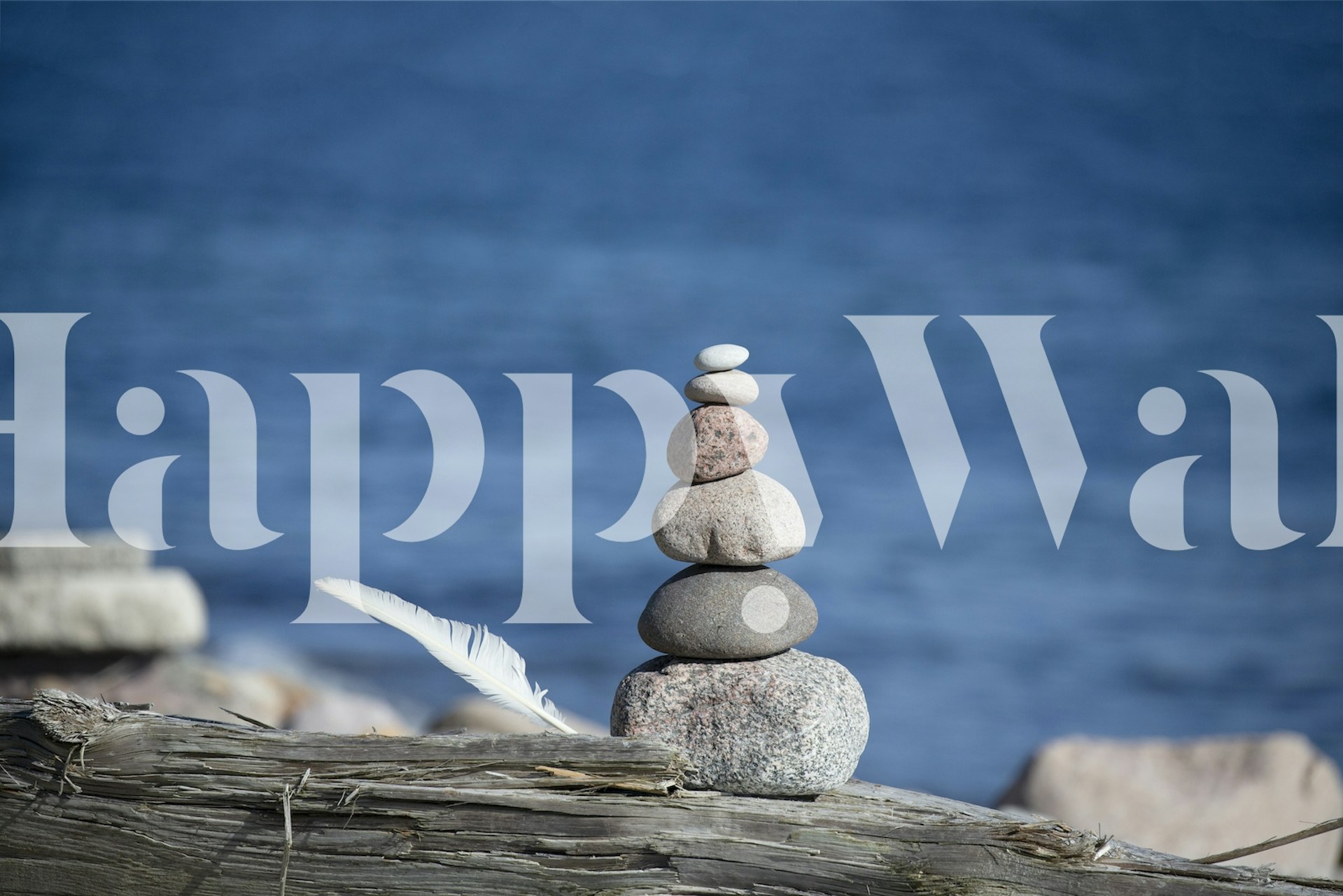 Stacked rocks balanced on a log near blue water wallpaper