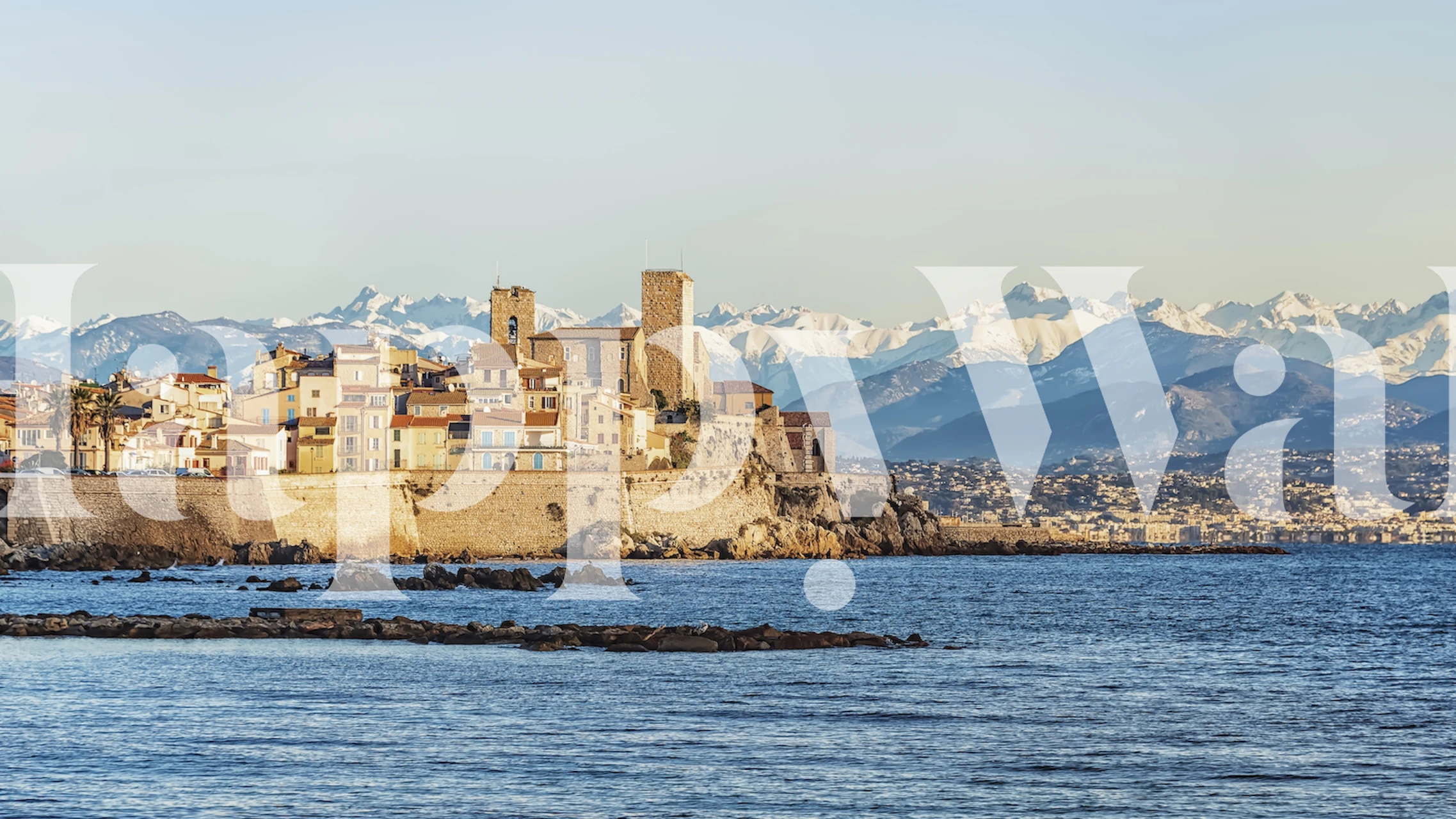 Old town coastal landscape of Antibes with historic buildings and snow-capped Alps in the background