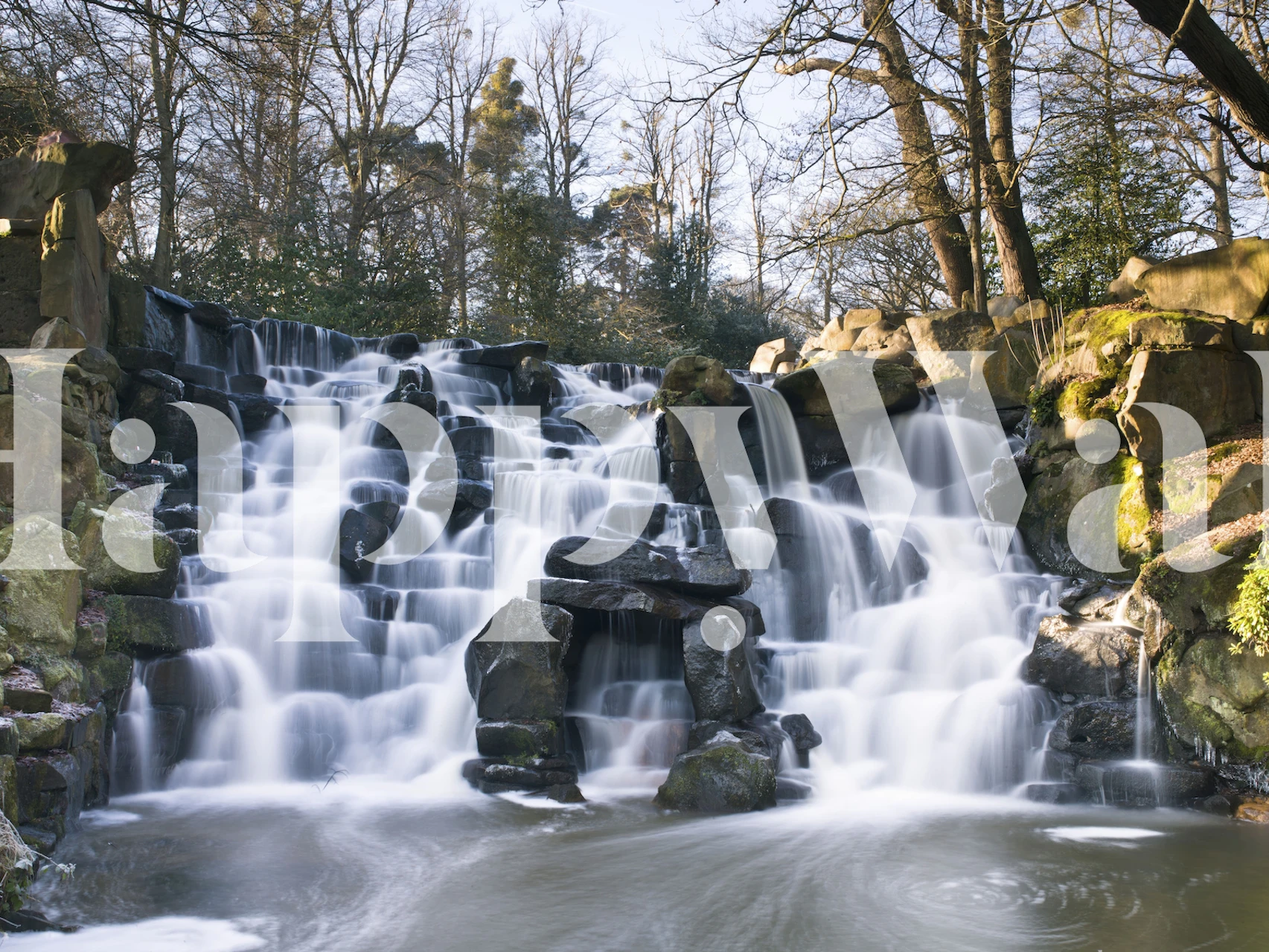 Waterfall cascading over rocks surrounded by trees wallpaper