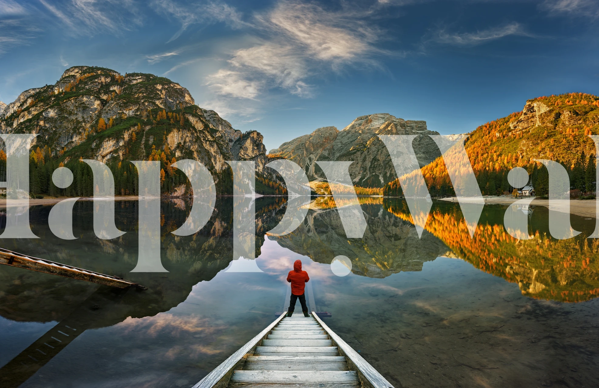 Person standing on a jetty in a serene mountain lake scene at sunrise