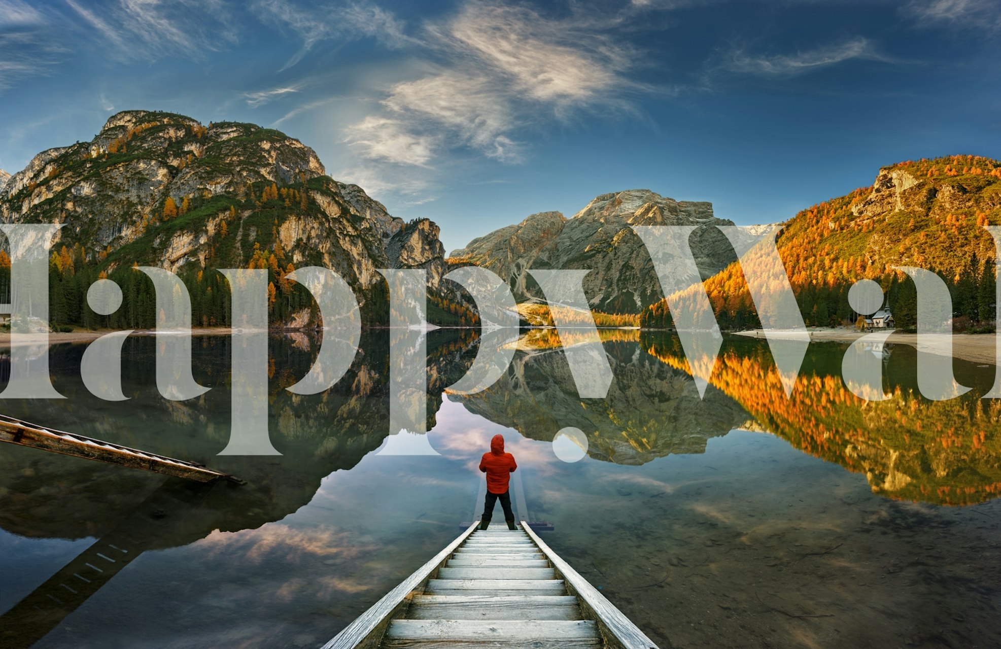 Person standing on a jetty in a serene mountain lake scene at sunrise