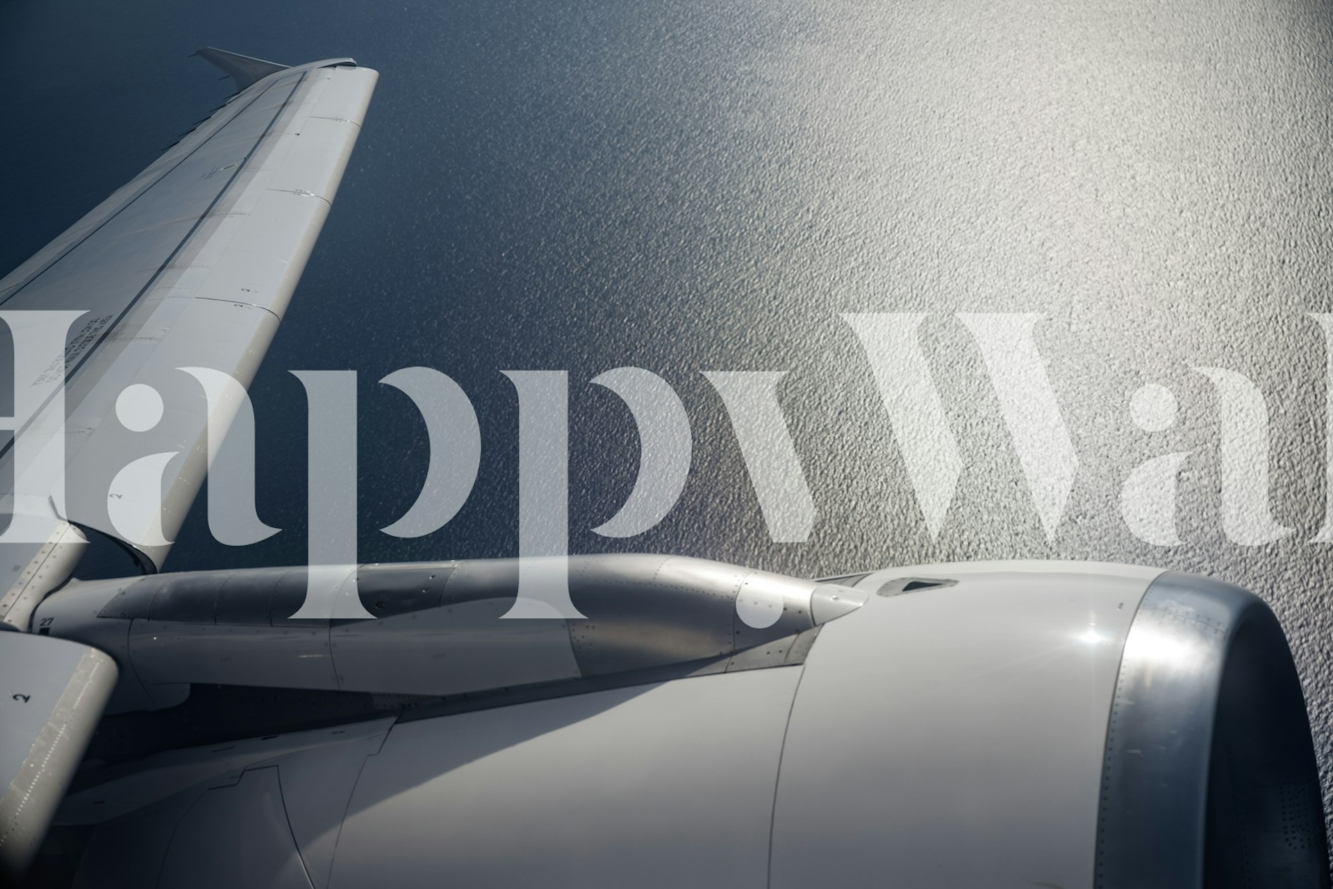 Airplane wing above ocean water reflecting sunlight wallpaper